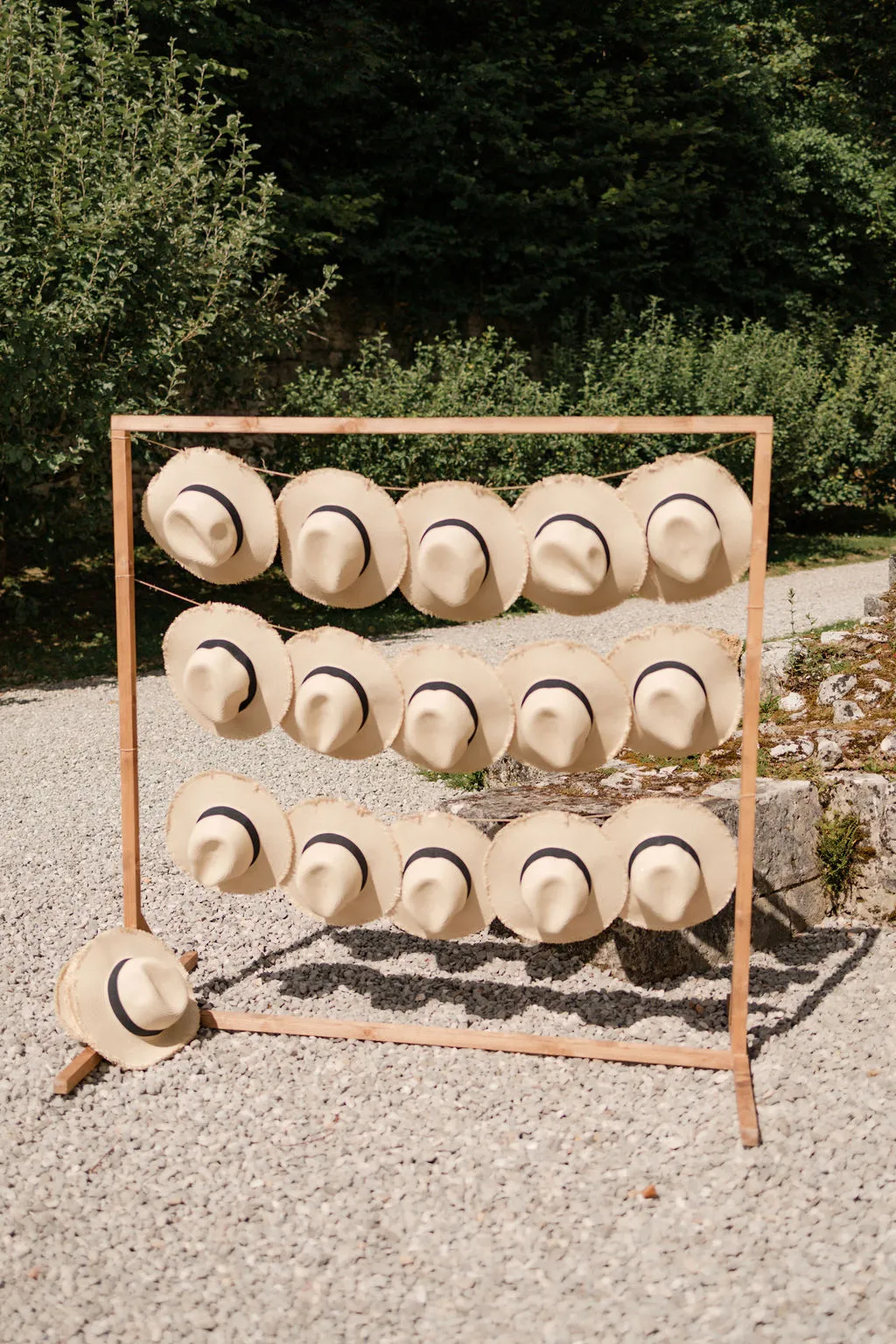Straw hats displayed on a wooden rack as wedding guest favors