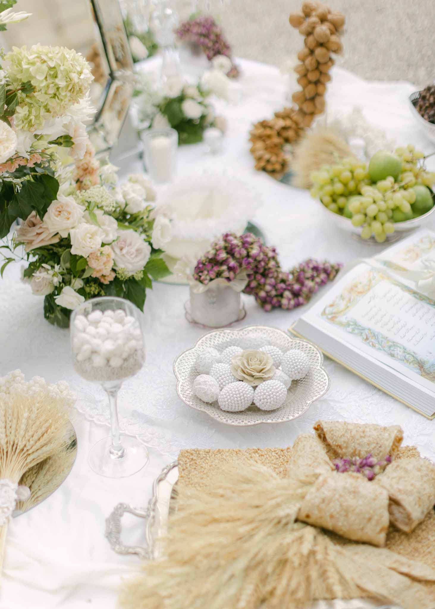 Overhead view of reception table setting with cream roses, white hydrangeas, mauve berries, and gold ribbon accents