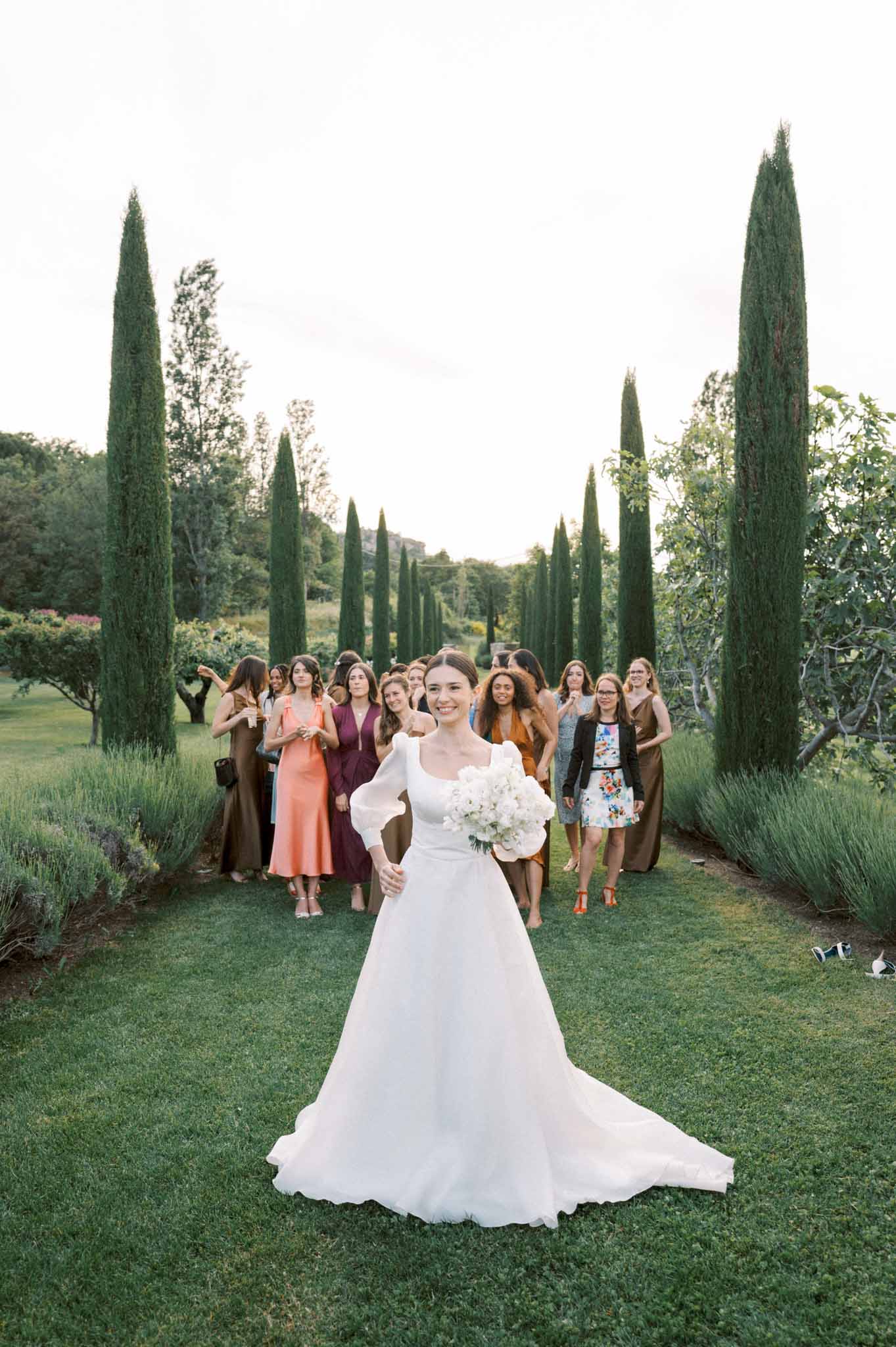 Bride with puff-sleeve gown and peony bouquet faces 15 guests on cypress-lined Provencal lawn