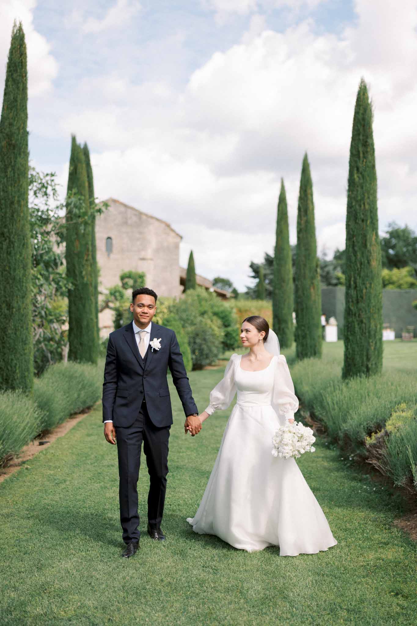 Bride and groom walking hand in hand in a garden