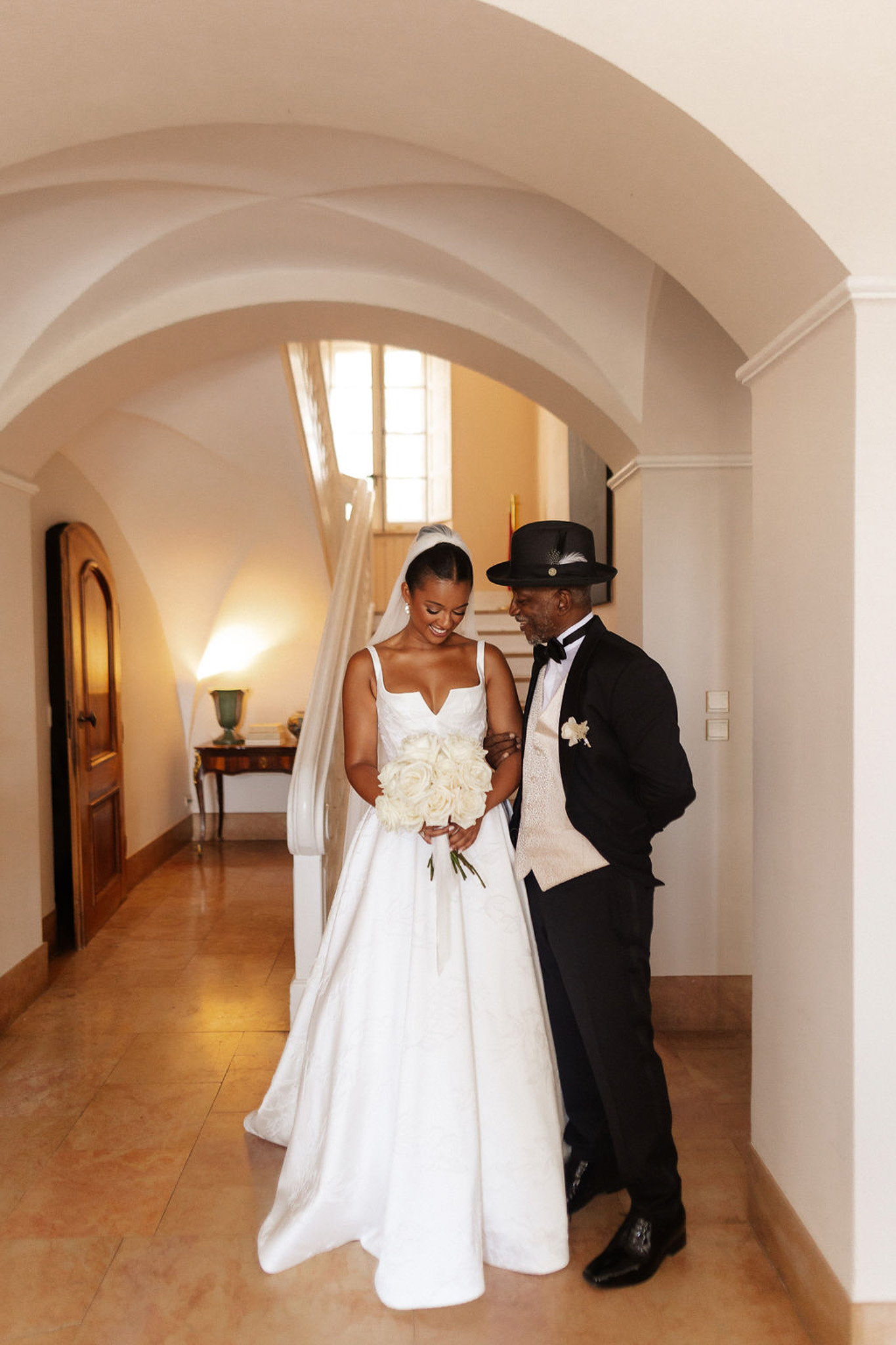 Bride and groom walking through classical arched corridor in intimate portrait moment