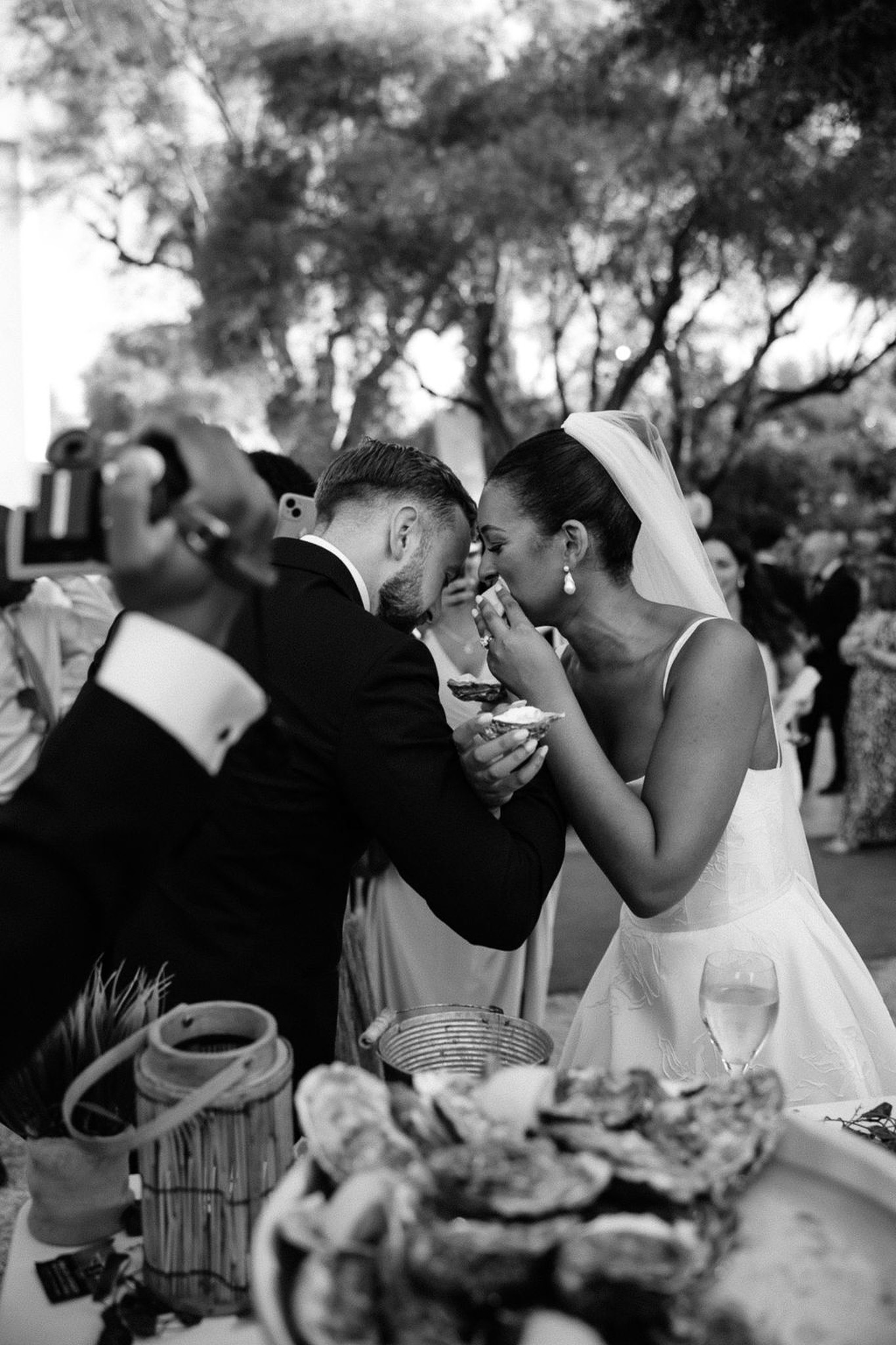 Bride and groom sharing food during outdoor wedding reception in garden setting