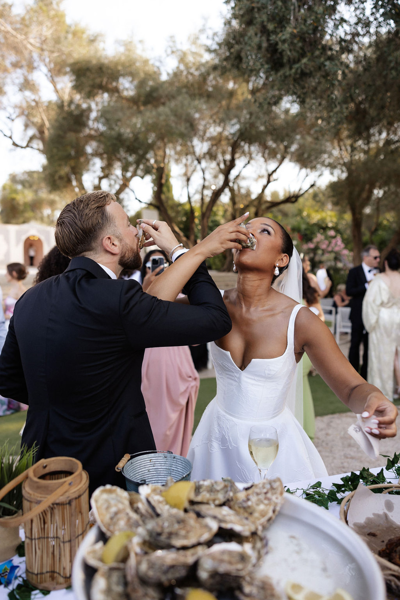 Bride and groom sharing oysters during cocktail hour at outdoor garden wedding reception