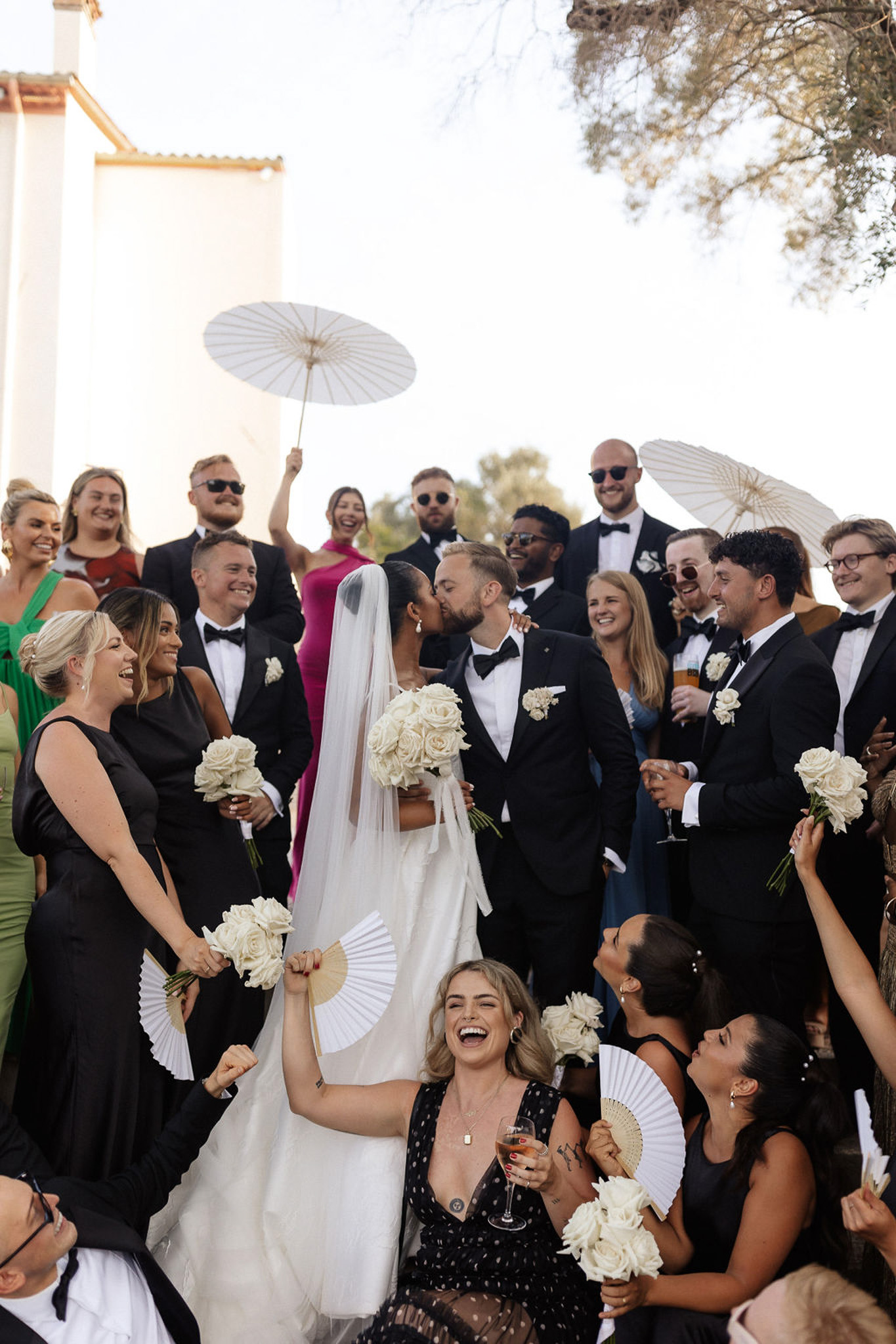 Wedding group portrait with bride, groom and 25 guests in outdoor courtyard during reception