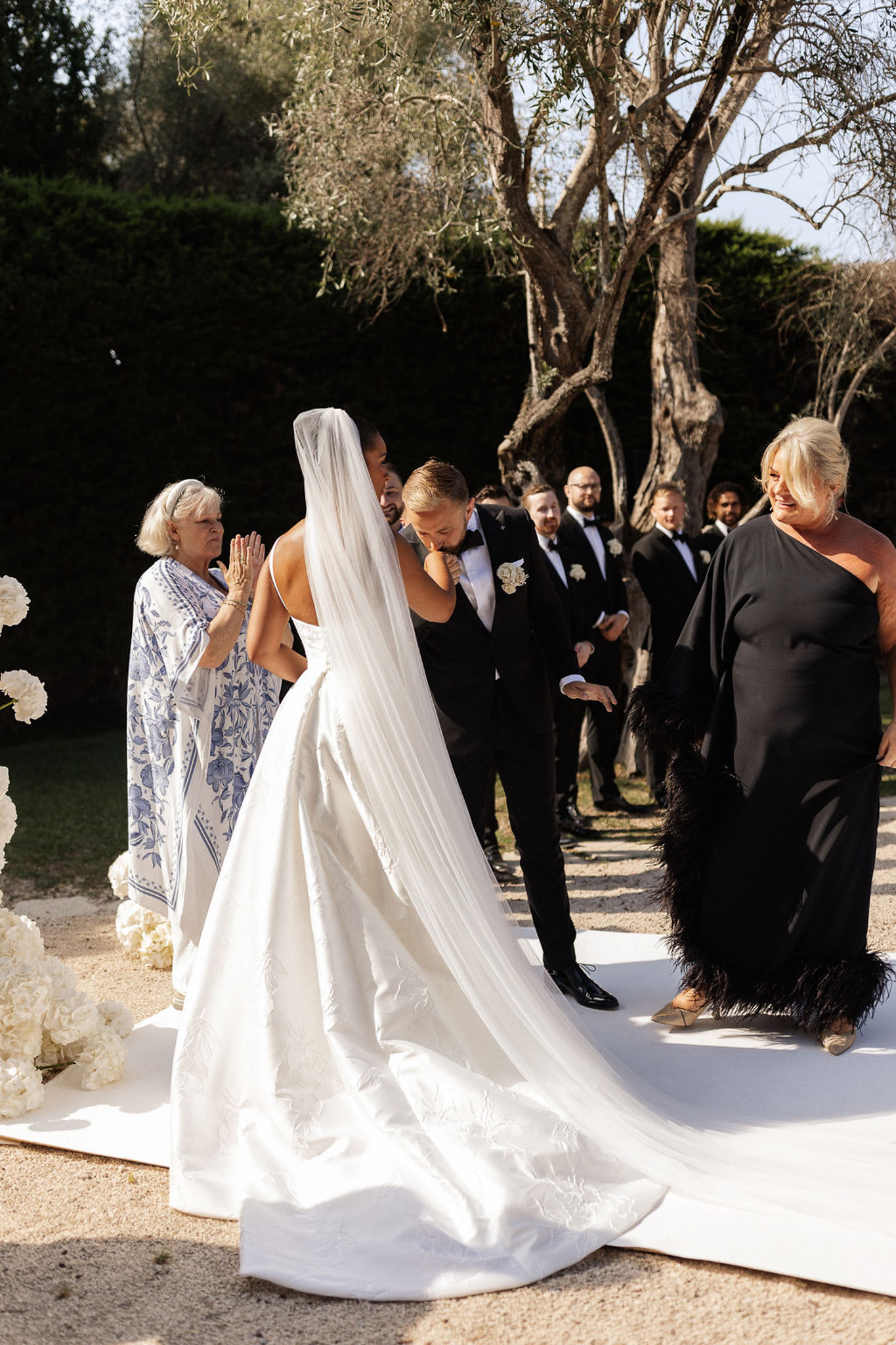 Outdoor wedding ceremony with bride walking down aisle in garden setting with guests