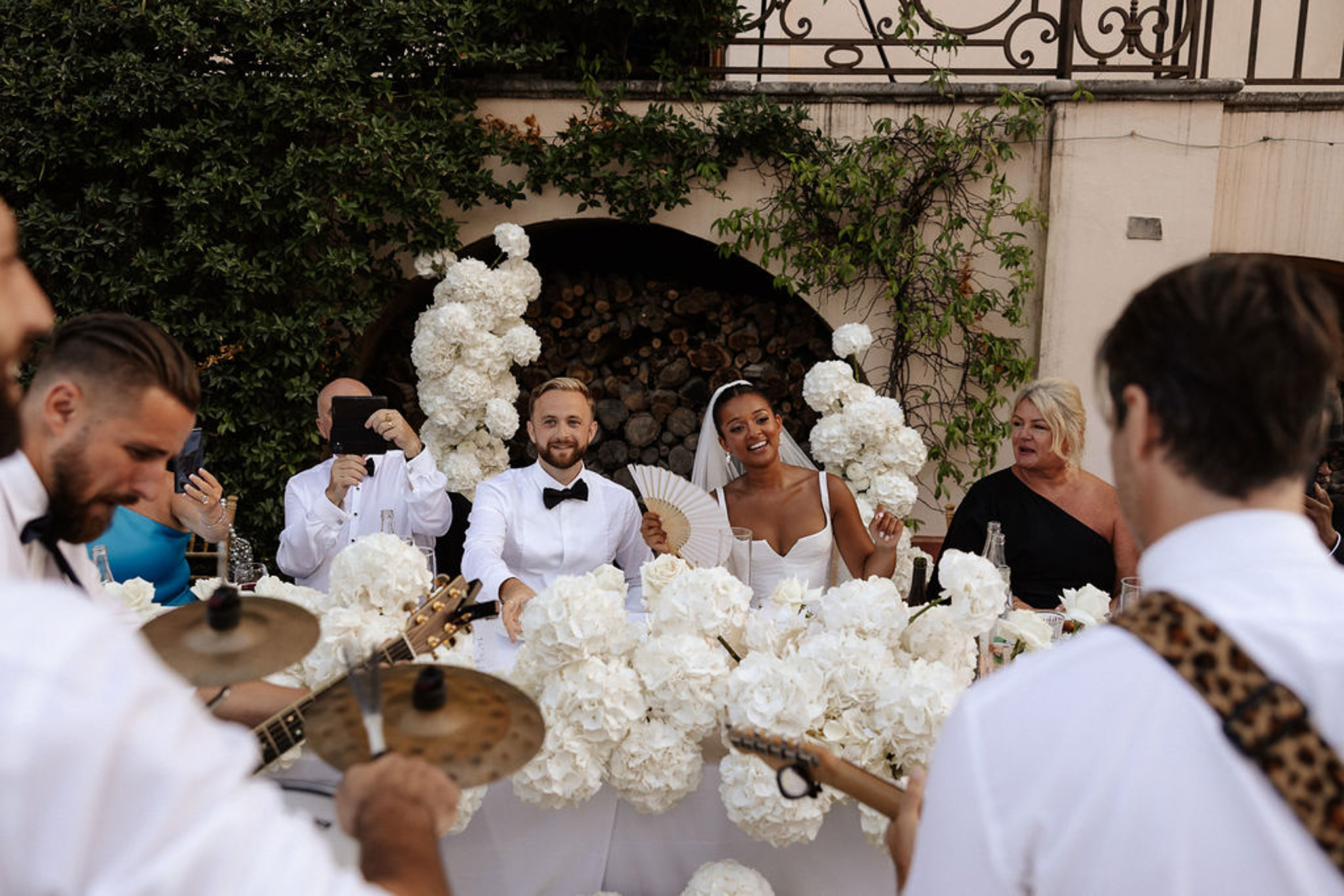 Bride and groom at sweetheart table during live band performance at outdoor courtyard reception