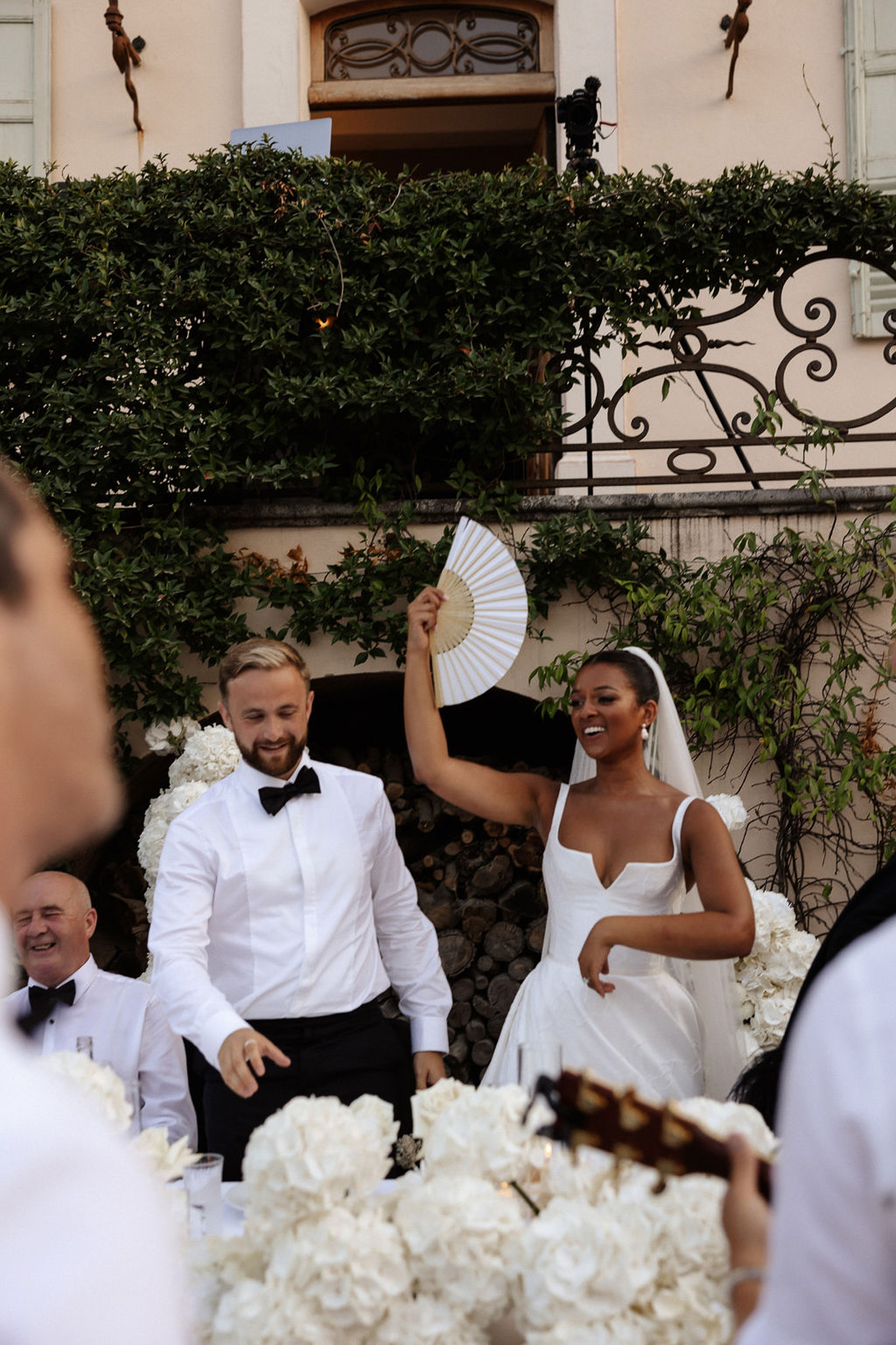 Bride and groom laughing together during reception in Mediterranean courtyard with white floral arrangements