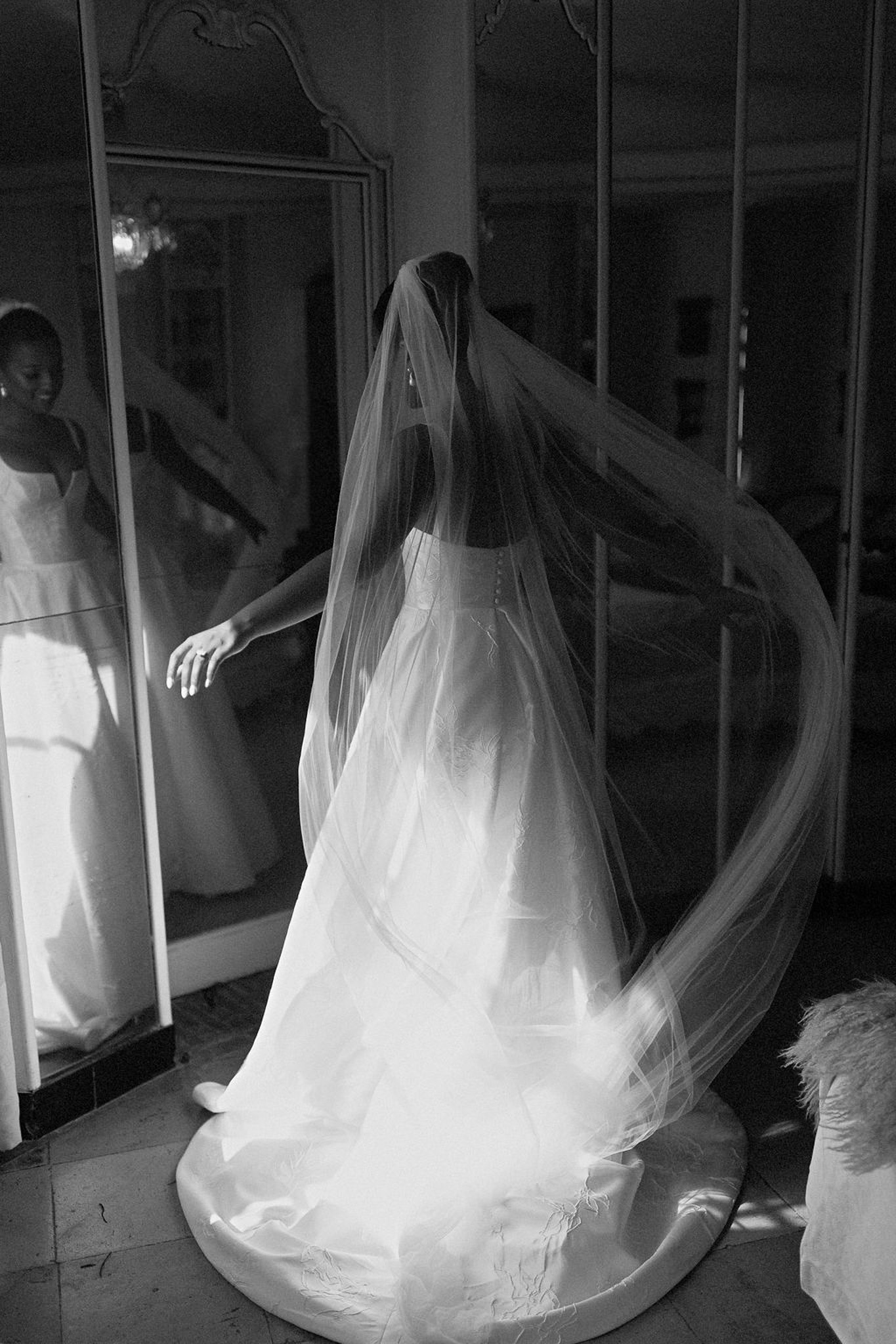 Bride in wedding dress and veil with bridesmaids getting ready in ornate indoor dressing room