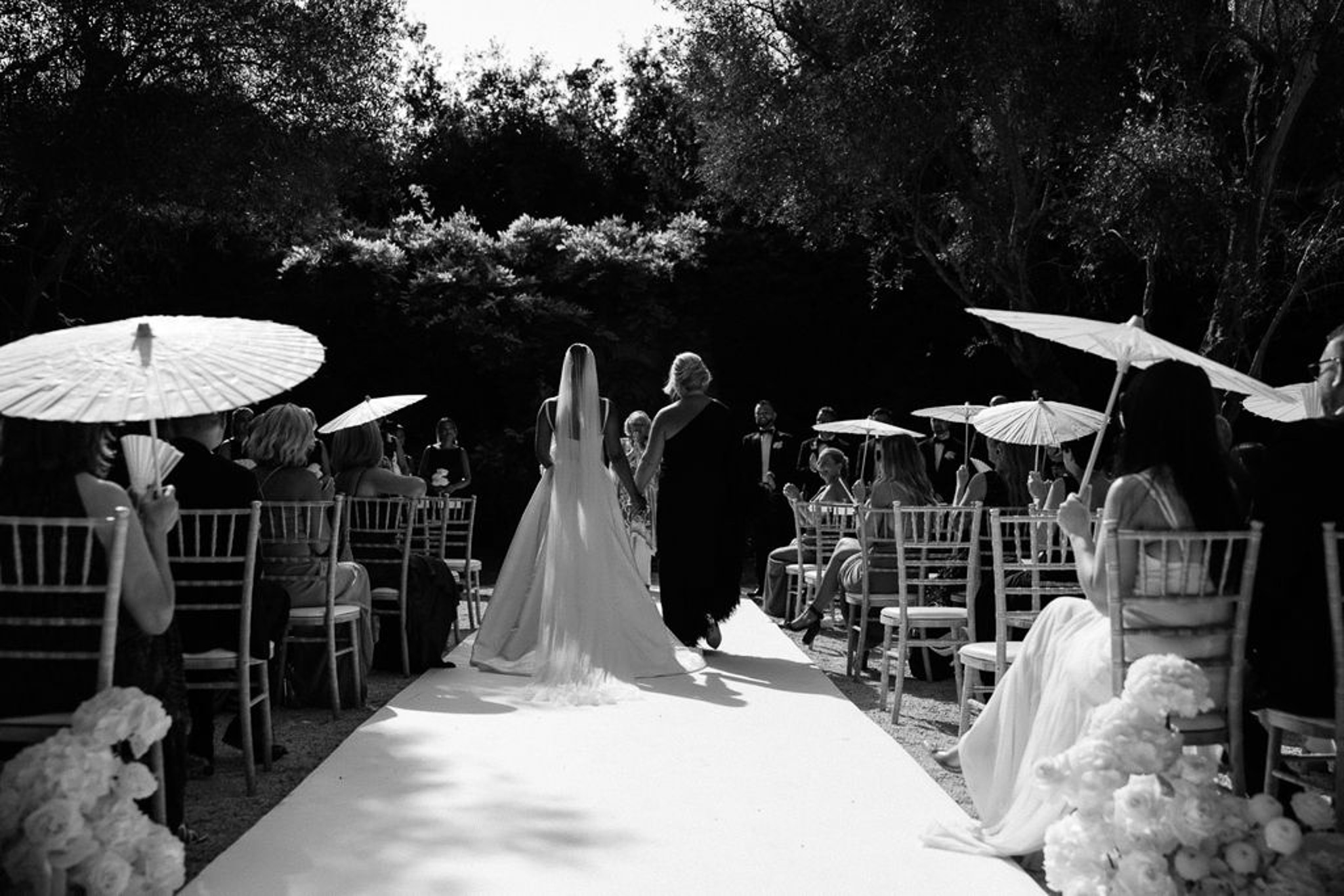Outdoor wedding ceremony with bride and groom at altar surrounded by seated guests in garden setting