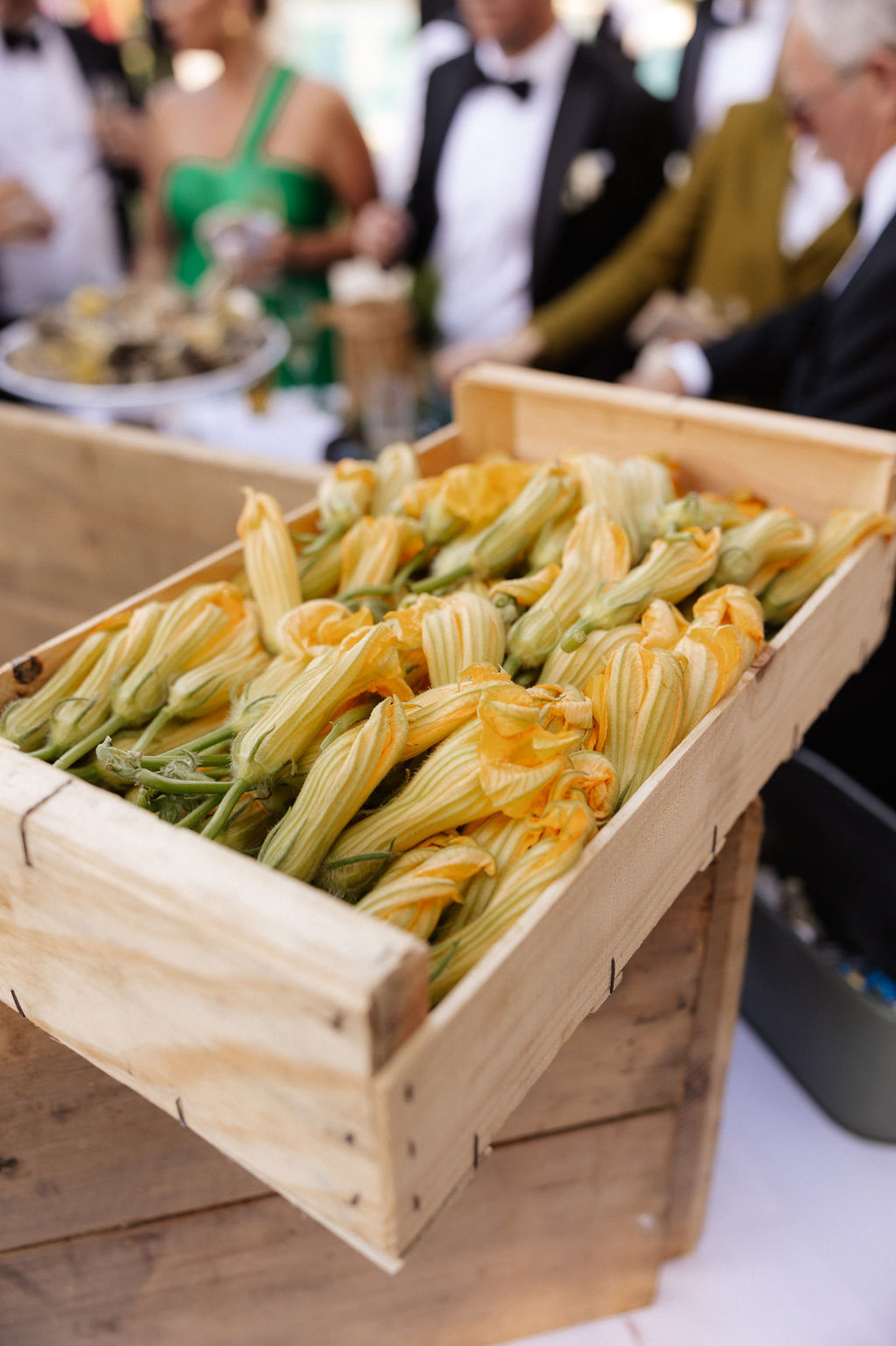 Squash blossoms in wooden crate as appetizer station at wedding reception