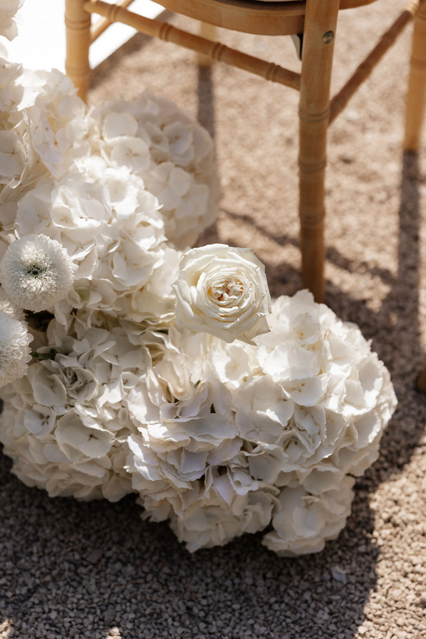 White hydrangea and ivory rose bridal bouquet detail at outdoor beach wedding ceremony