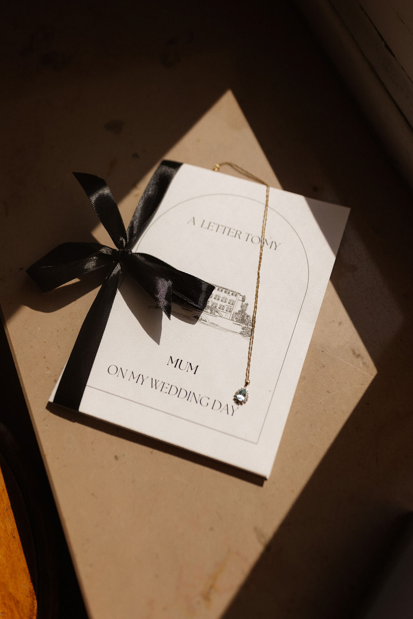 Wedding stationery flat lay with card, necklace and gift box in natural sunlight