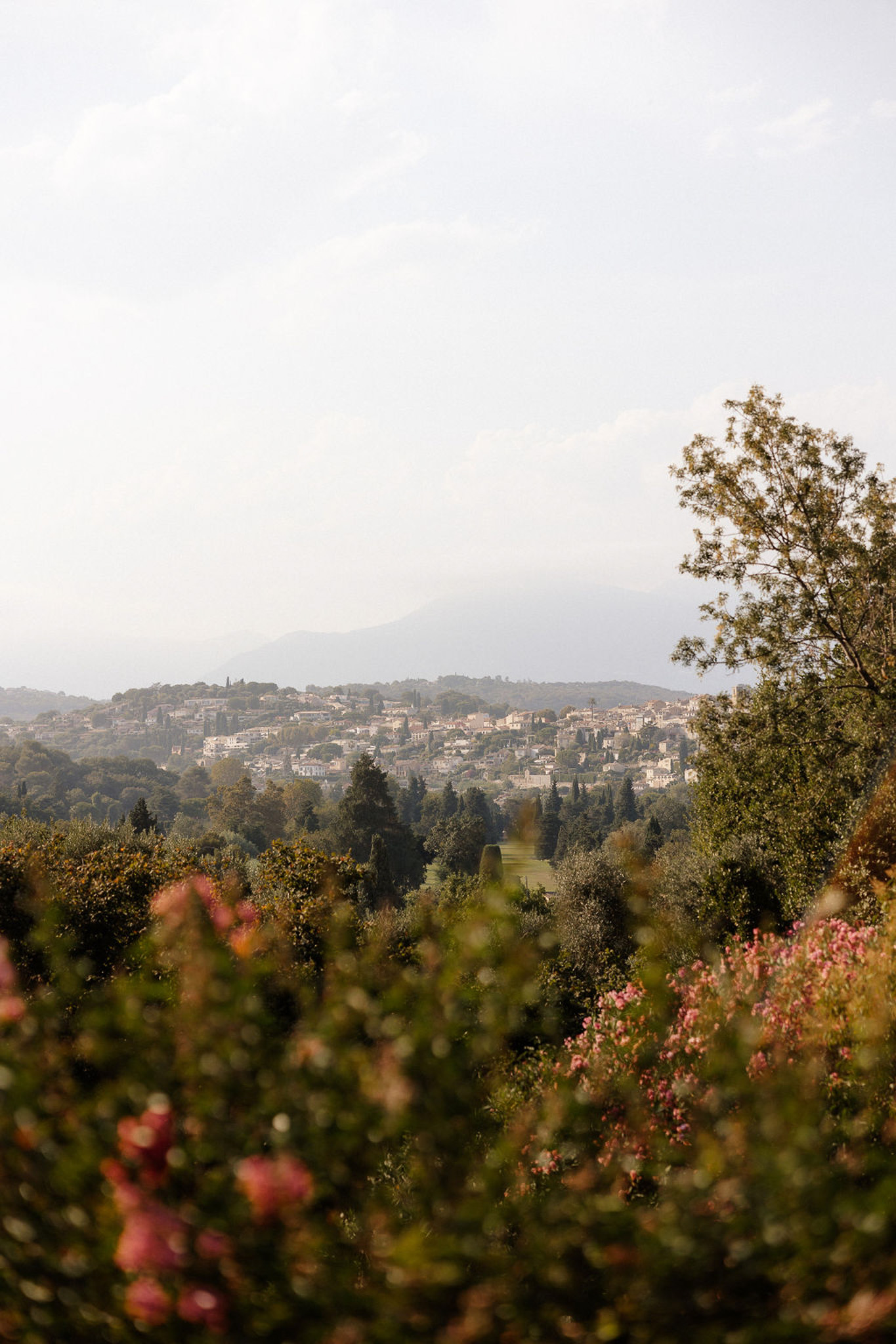 Wide landscape view of Tuscan hillside village with terracotta roofs and cypress trees from garden terrace