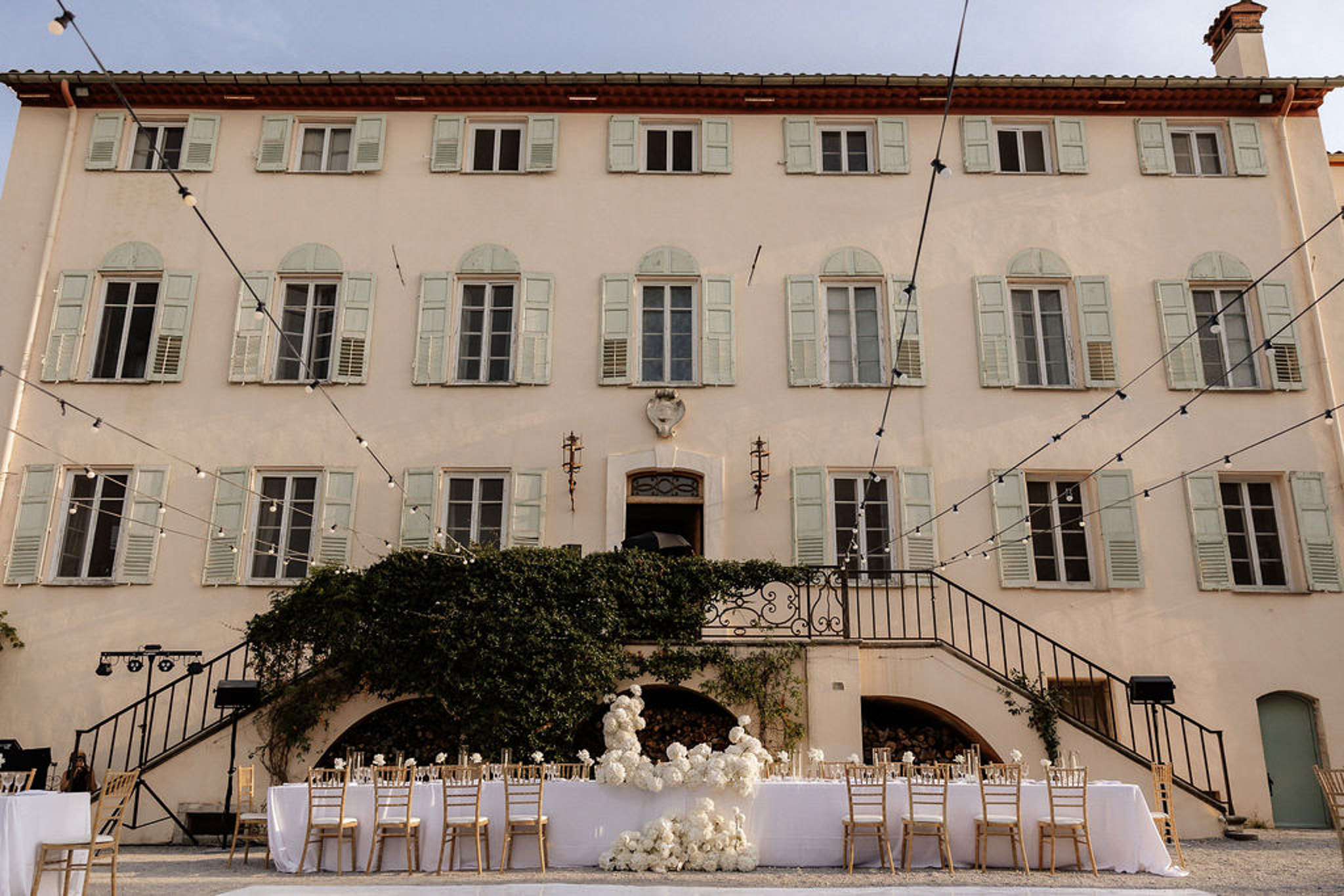 Wedding reception setup in European courtyard with classical peach building and string lights