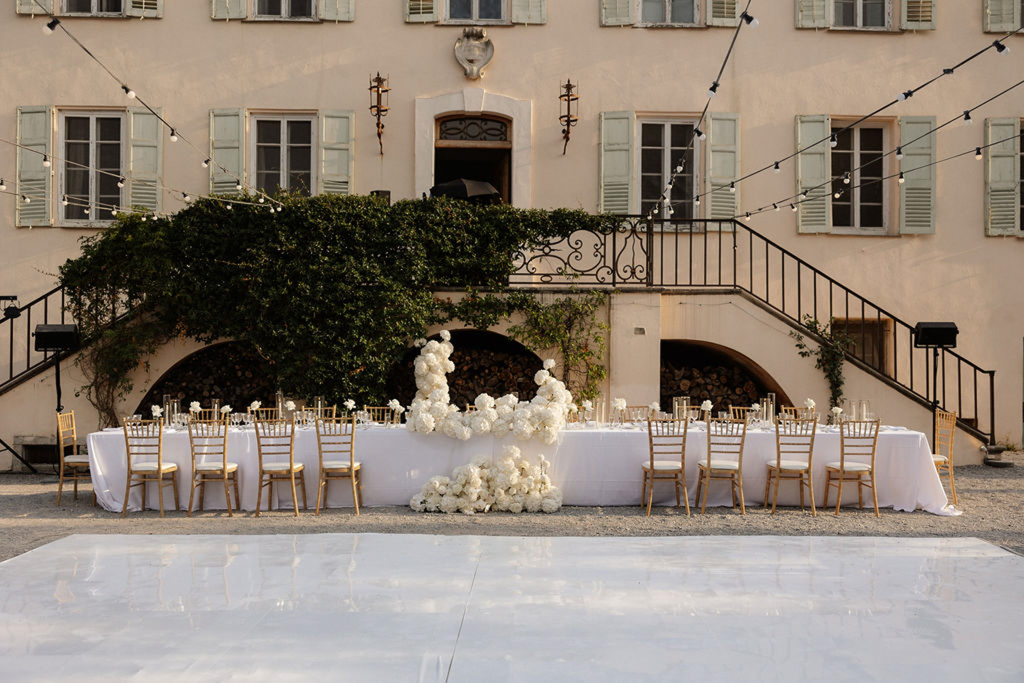 Reception setup in European stone courtyard with white florals and elegant architecture