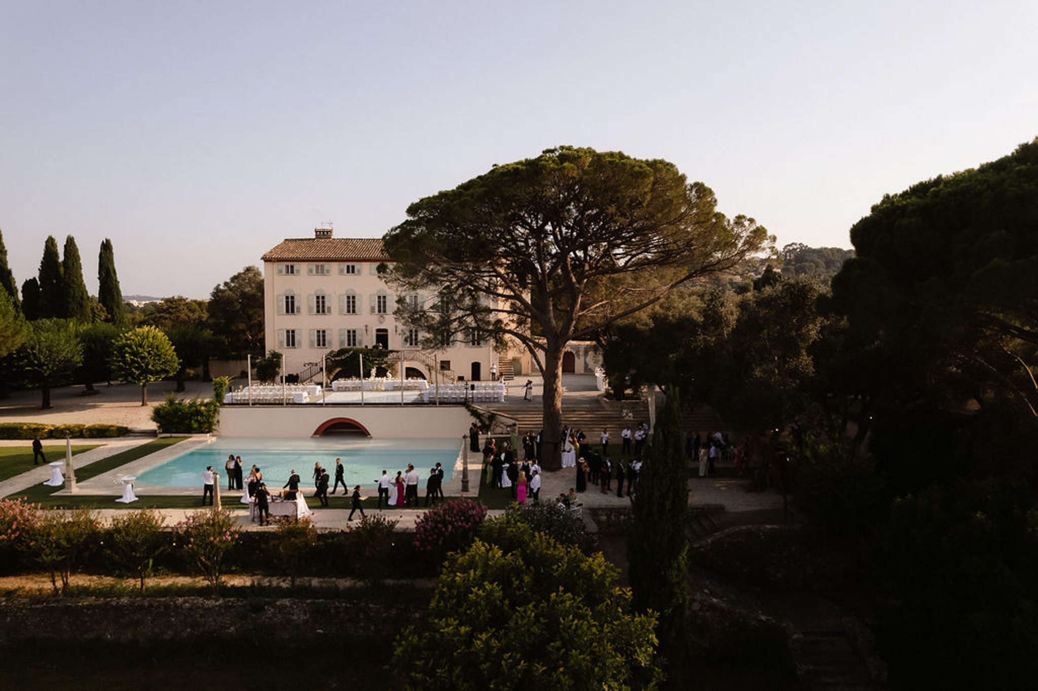 Aerial view of wedding reception around turquoise pool at Mediterranean villa estate with formal gardens