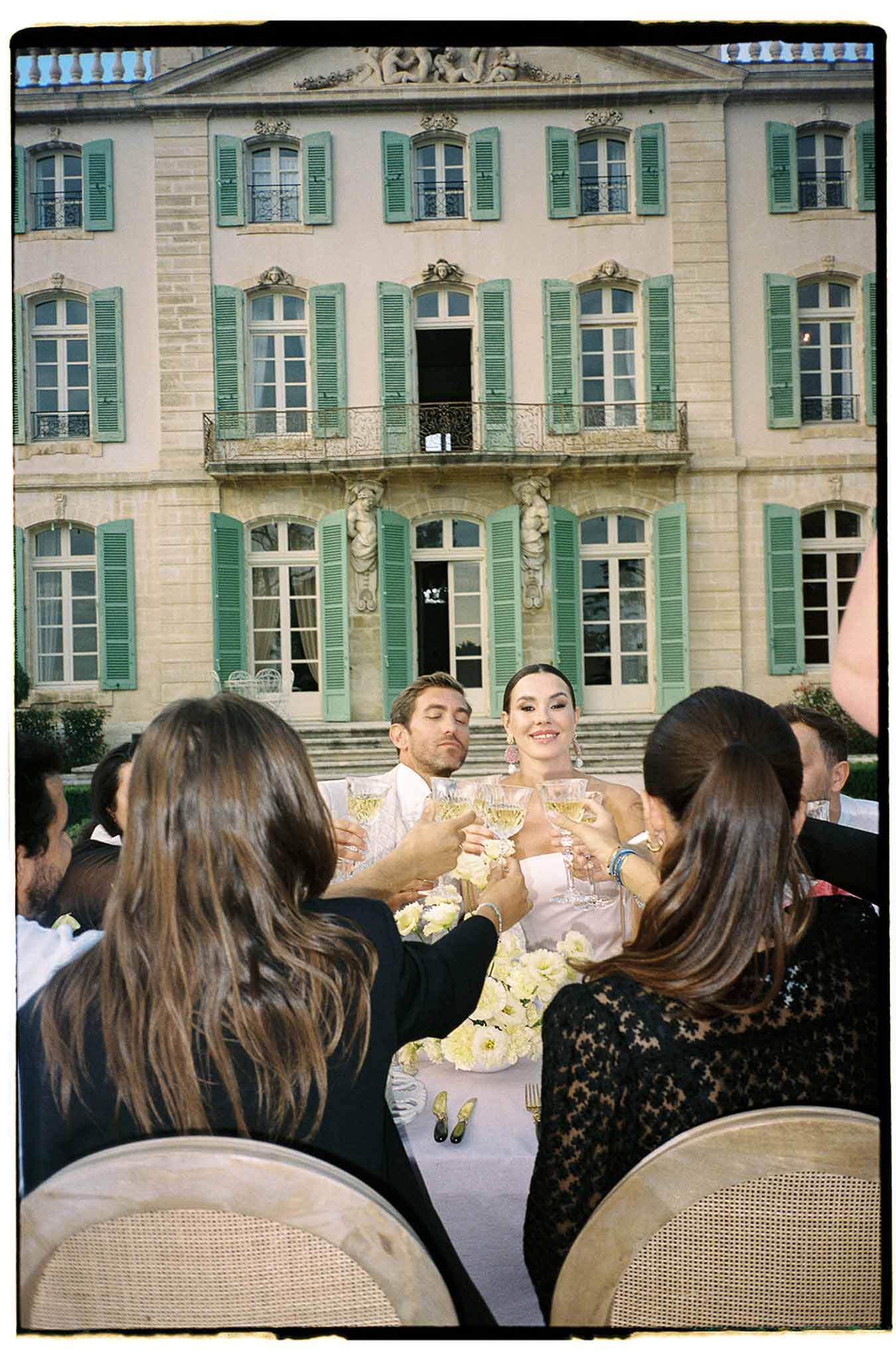 Wedding reception toast in château courtyard with guests raising champagne glasses