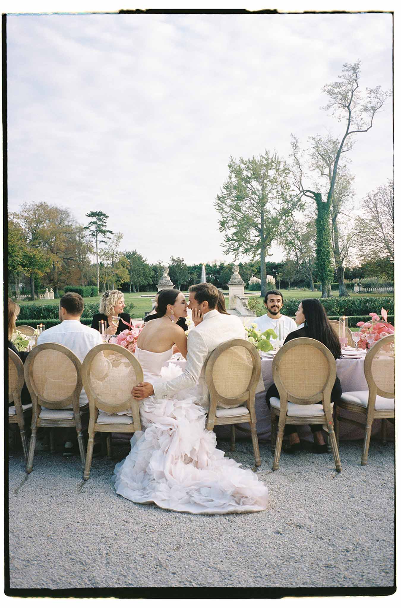 Bride and groom at outdoor reception dinner table in formal garden setting