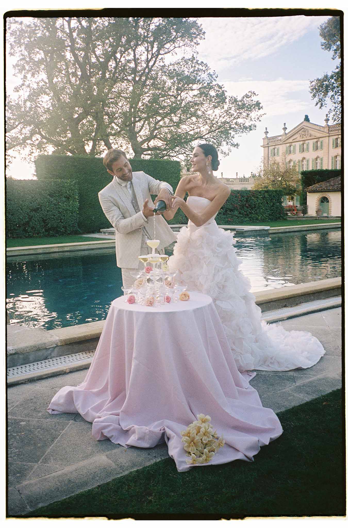 Bride and groom champagne toast at Italian villa garden terrace with reflecting pool