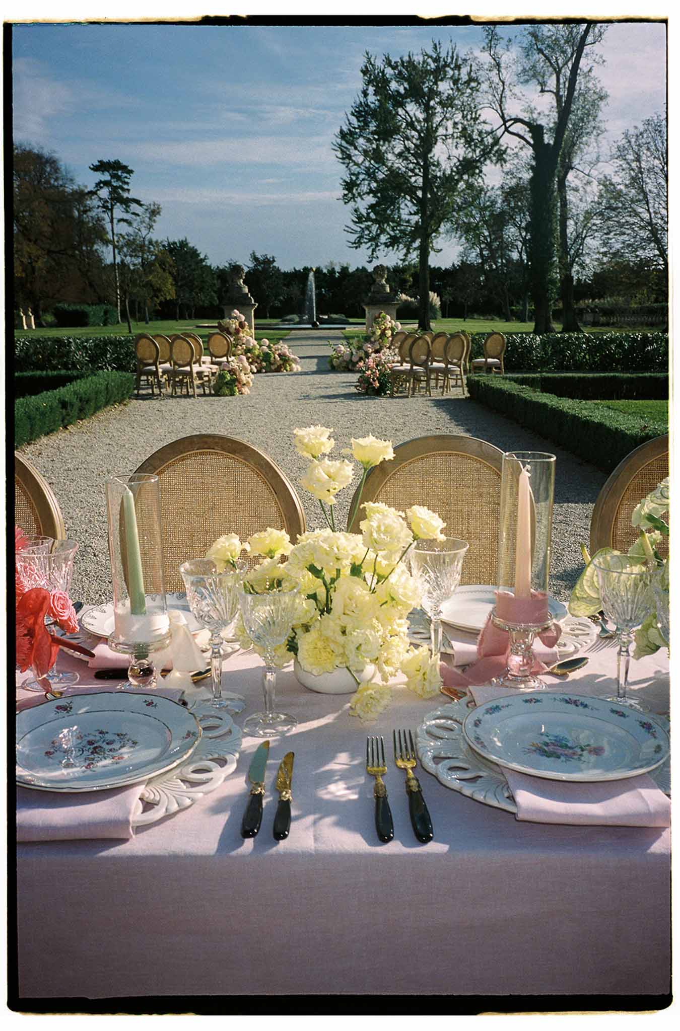 Elegant table setting with floral centerpieces at outdoor garden wedding reception