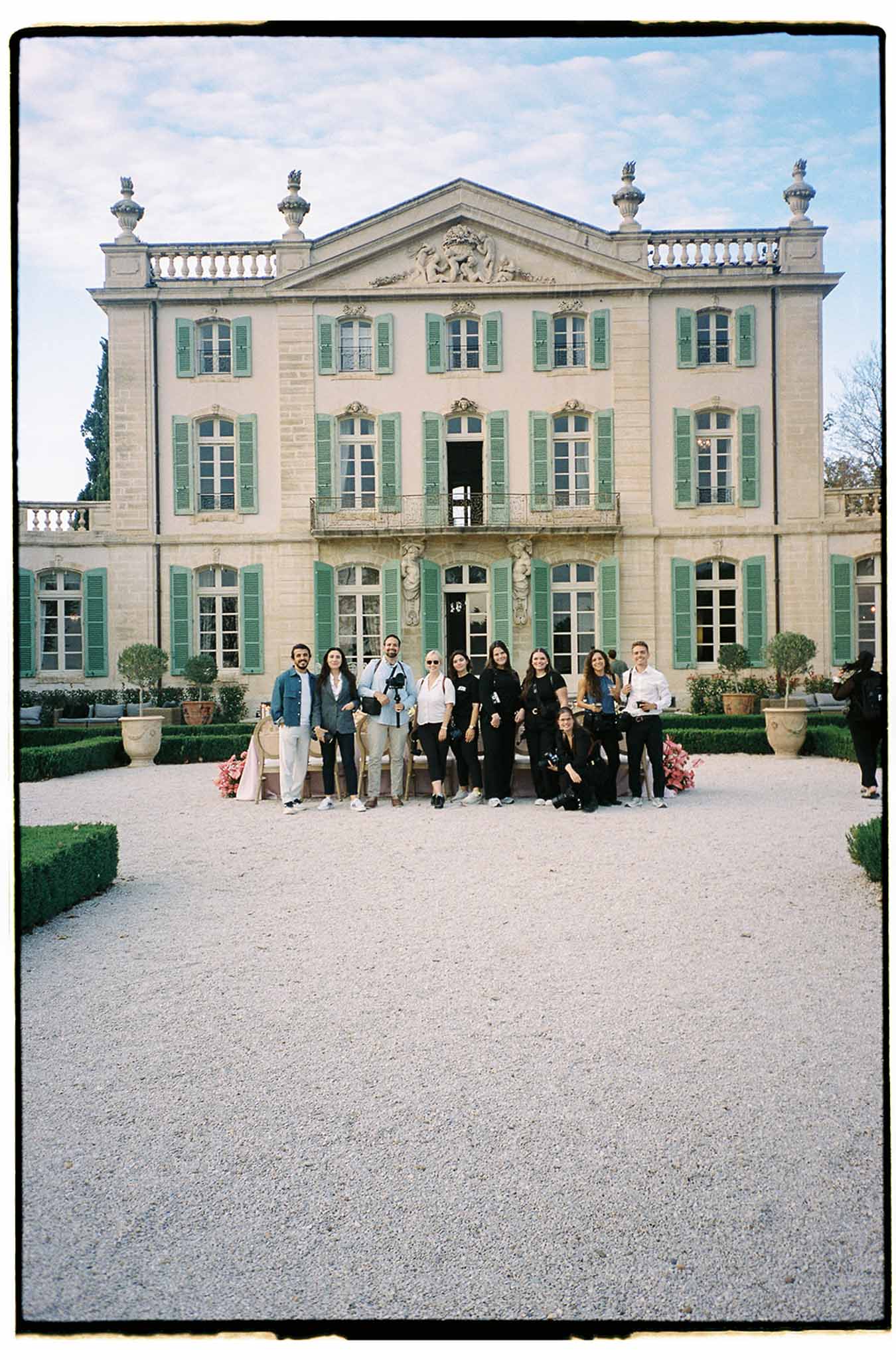 Wedding party group portrait at French neoclassical mansion courtyard