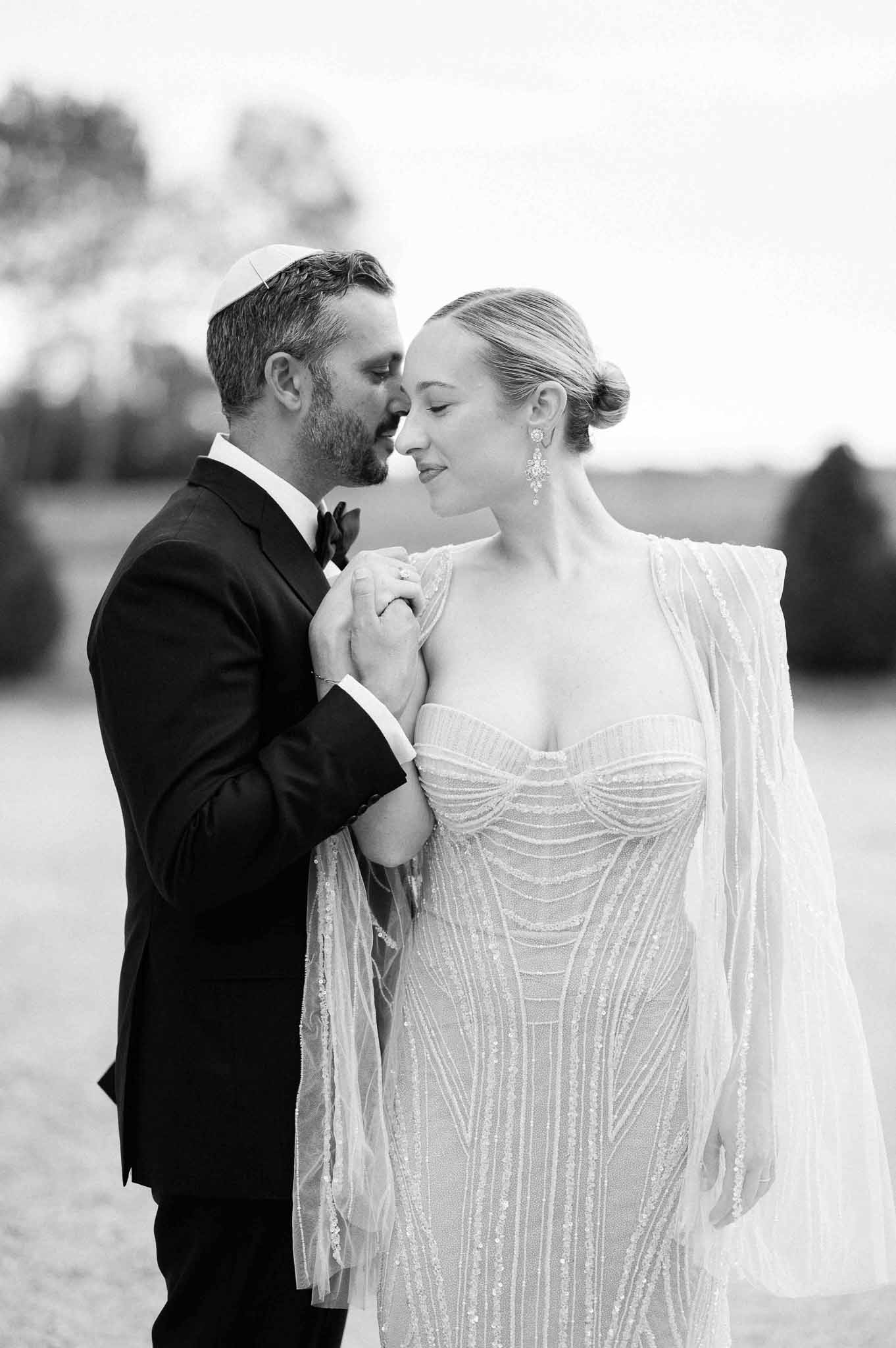Black and white portrait of bride and groom in formal wedding attire outdoors