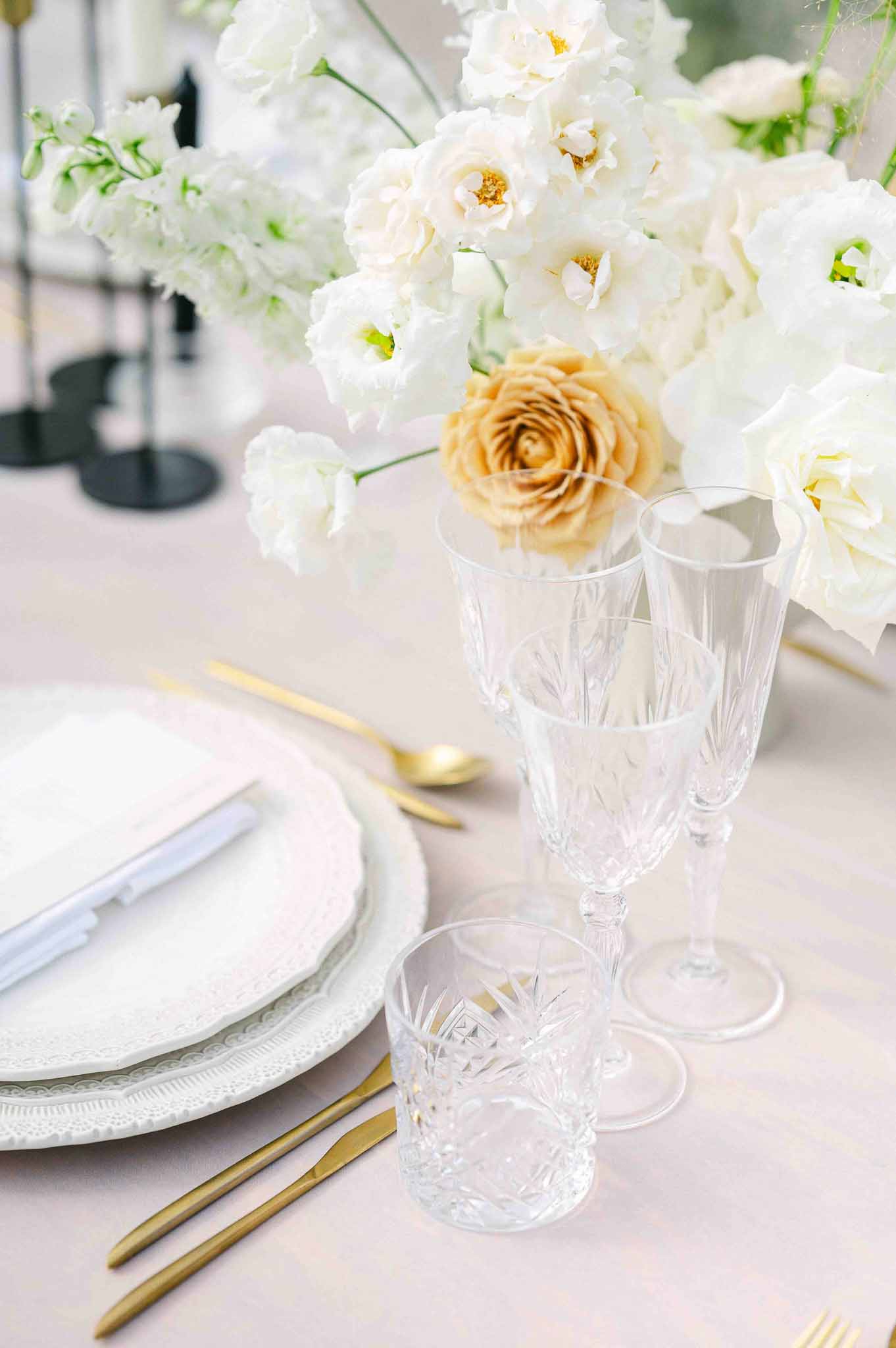 Reception table setting with ivory orchids and gold cutlery at wedding venue