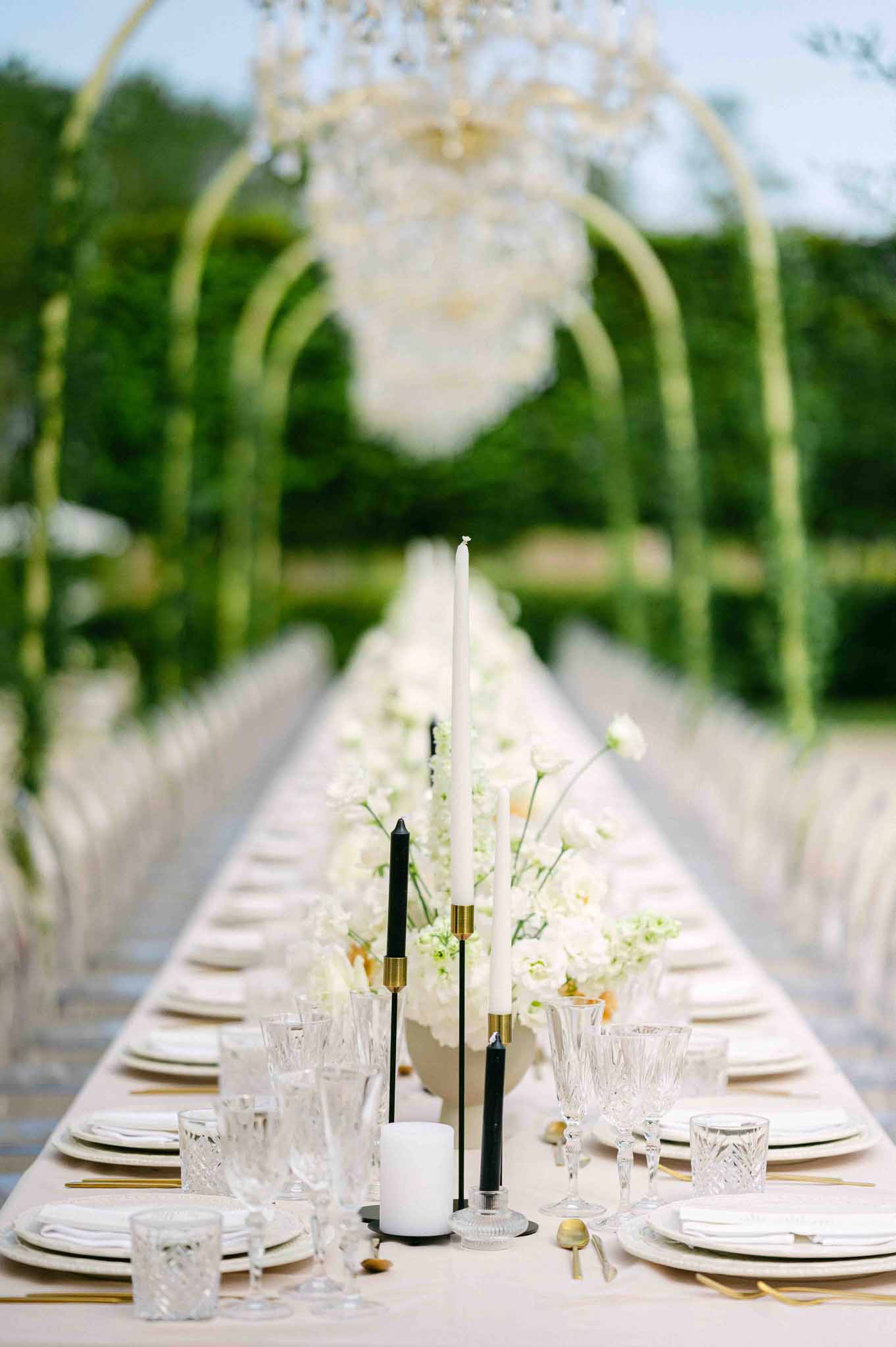 Elegant outdoor reception table with white florals and gold accents in garden setting