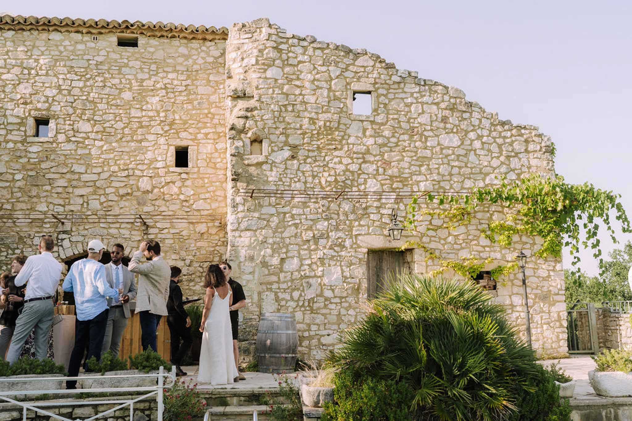 Bride and guests during cocktail hour at historic stone venue with Mediterranean gardens