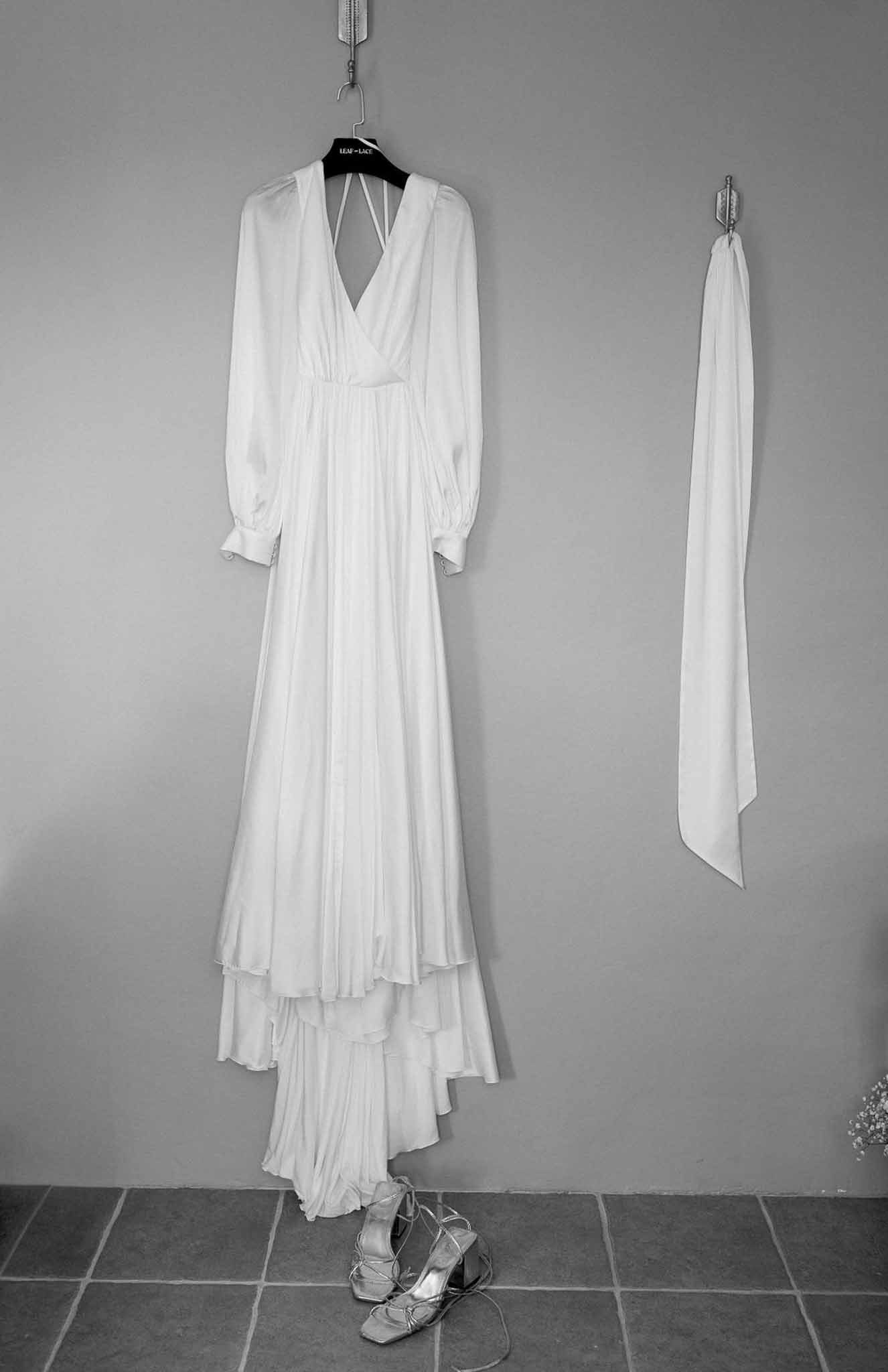 Bride's ivory wedding dress and silver heels hanging during getting ready preparations
