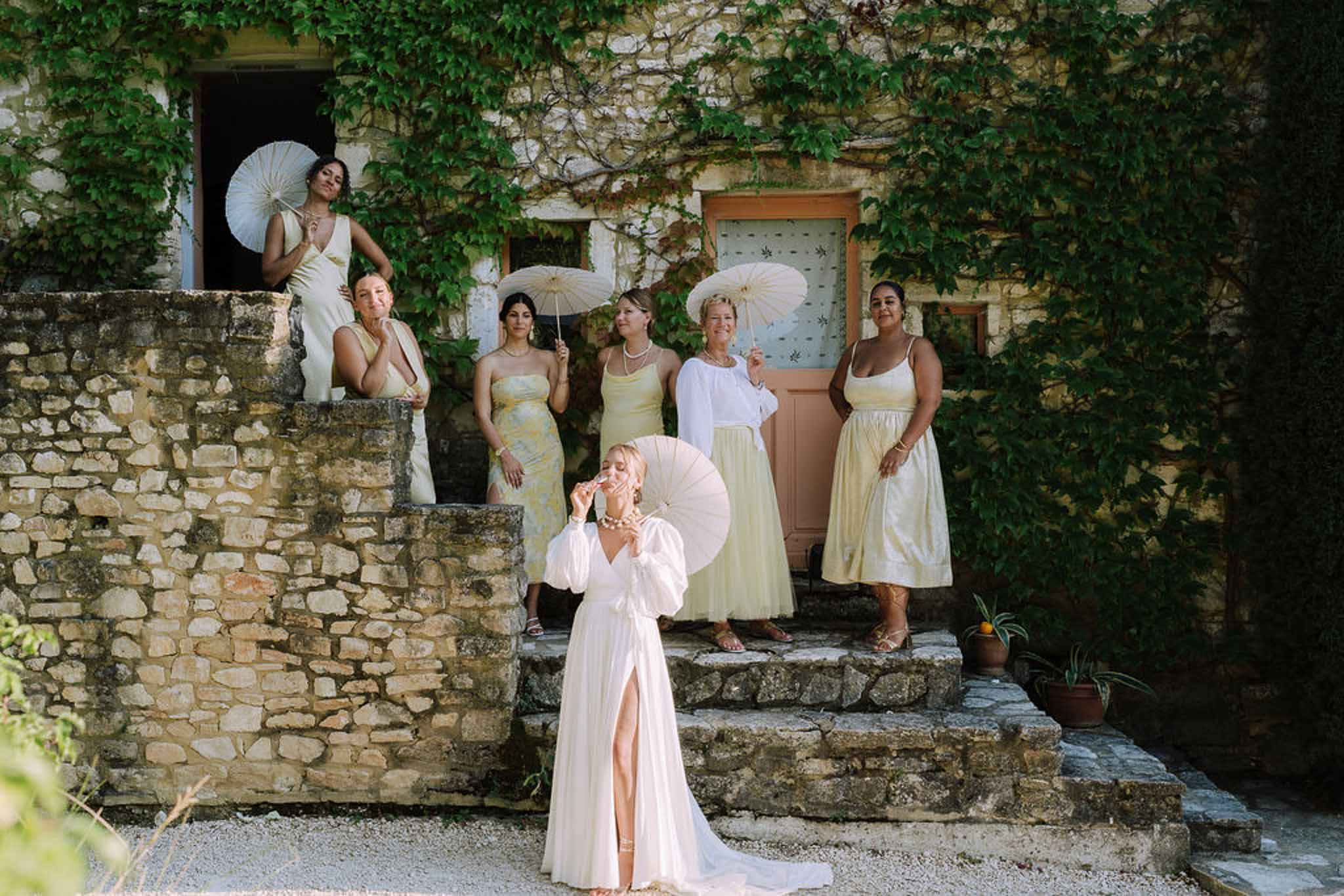 Bride and bridesmaids portrait with parasols at historic stone courtyard