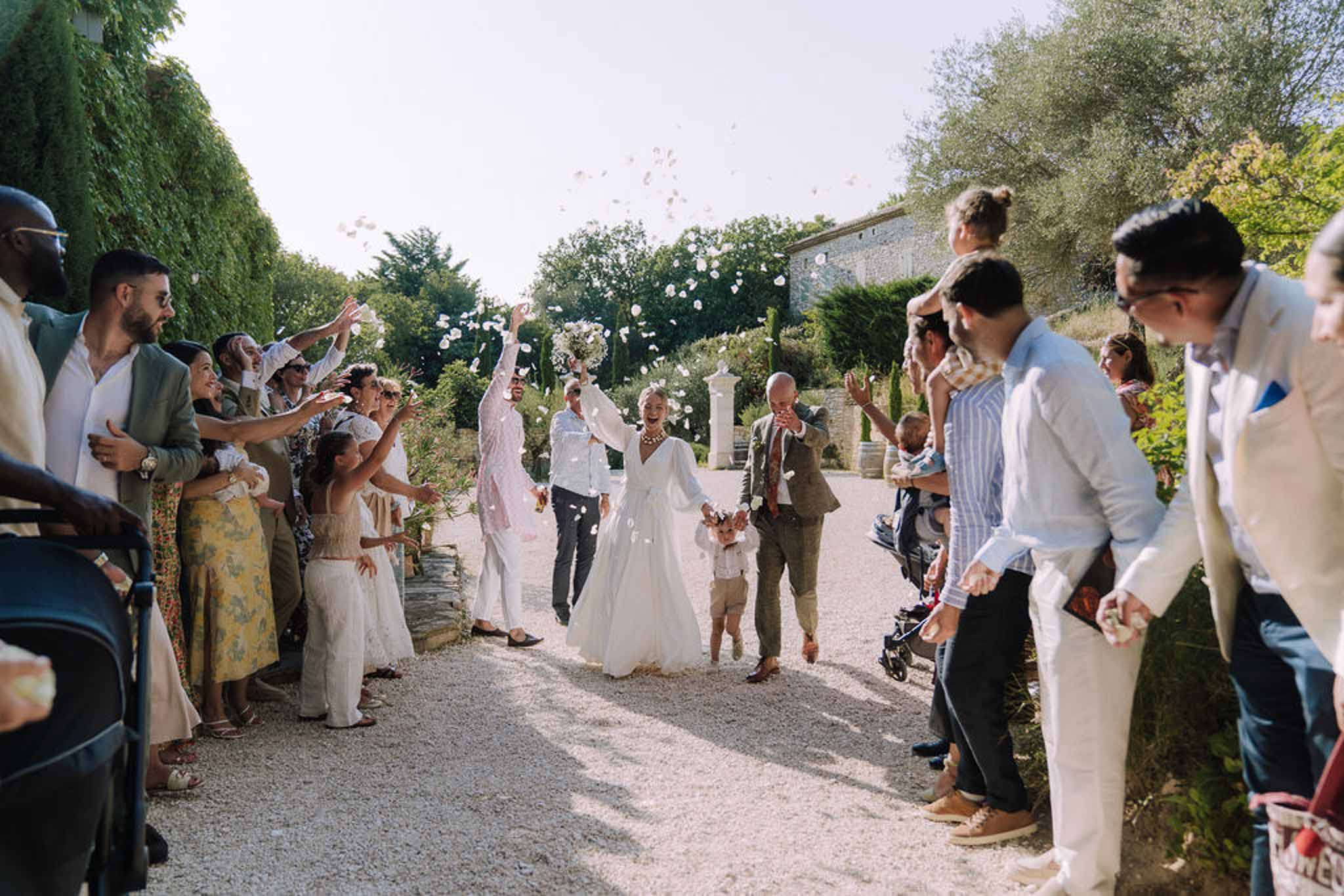 Bride and groom walking down pathway during wedding recessional at outdoor garden courtyard