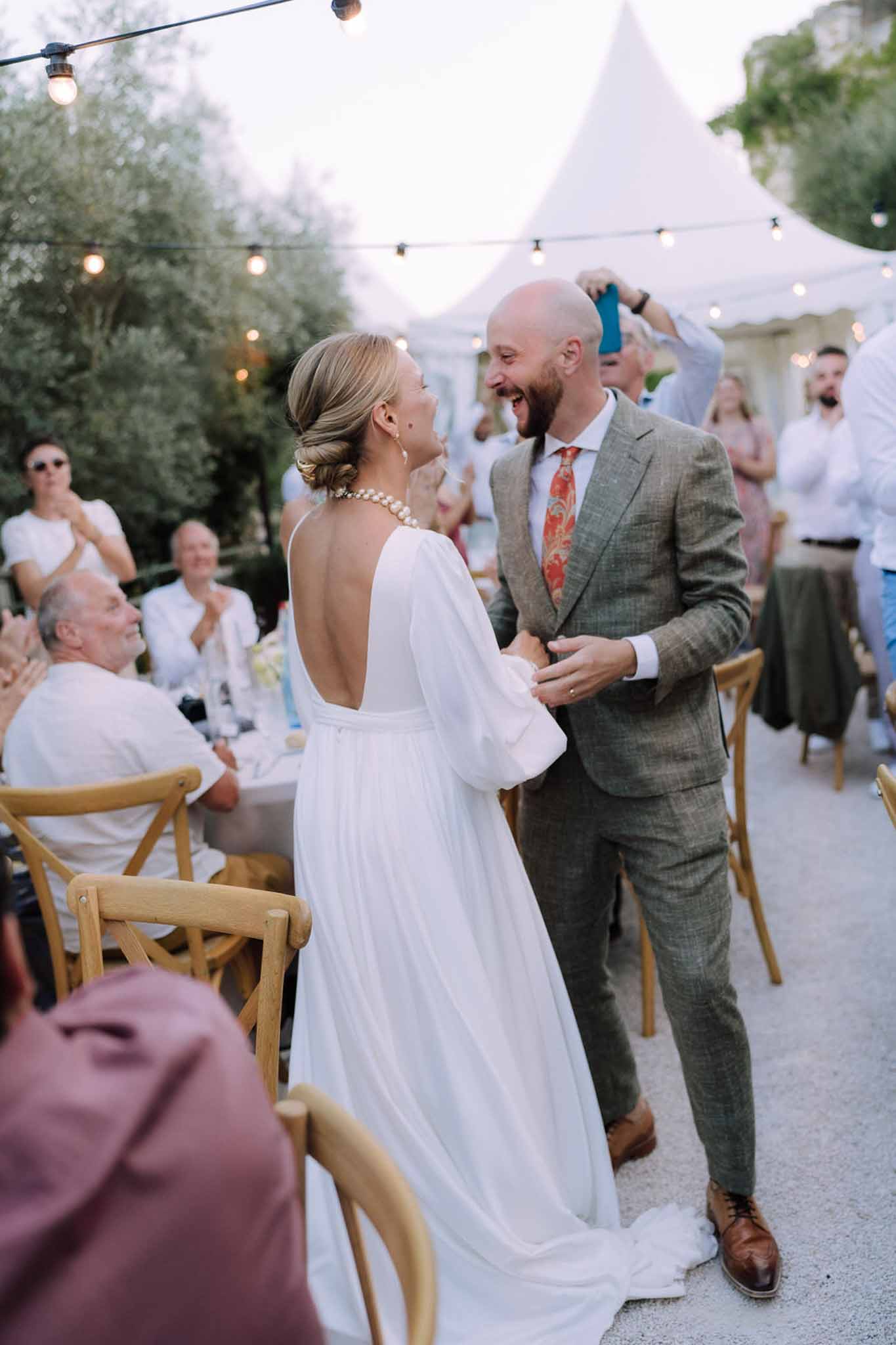 Couple's first dance at outdoor tent reception with Edison bulb lighting and olive trees