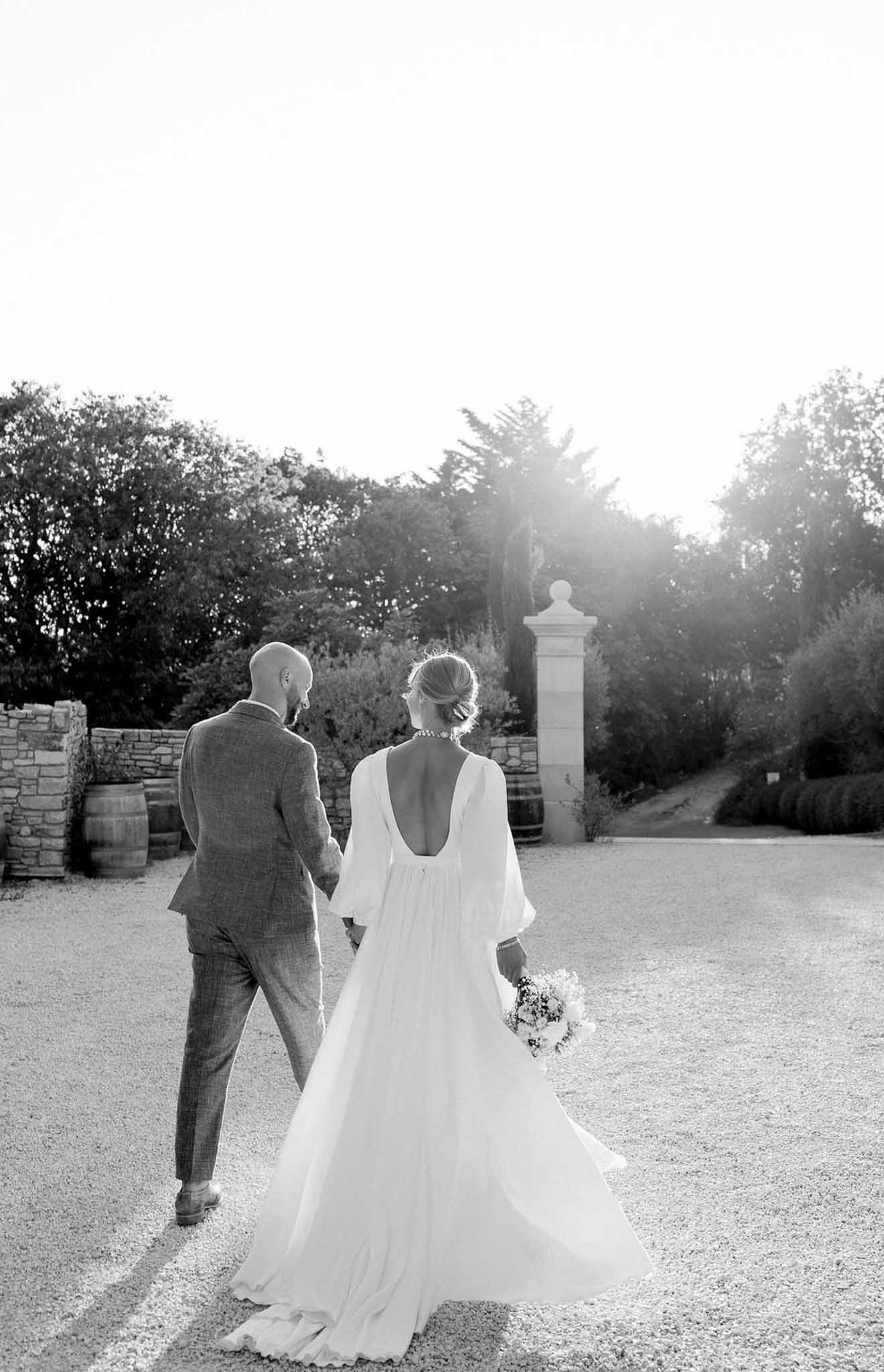 Bride and groom walking hand-in-hand across courtyard at vineyard estate wedding venue