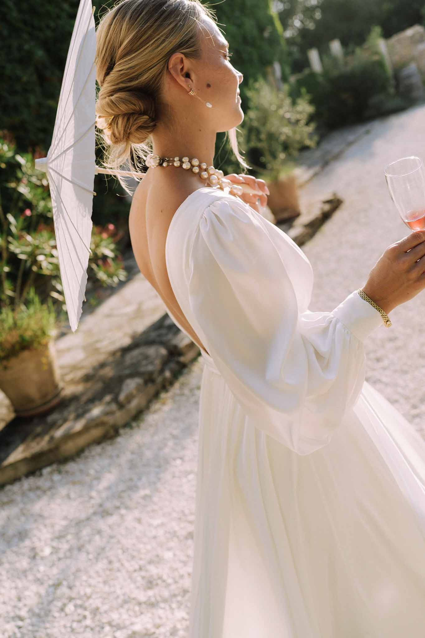 Bride in ivory gown holding cocktail during outdoor garden reception