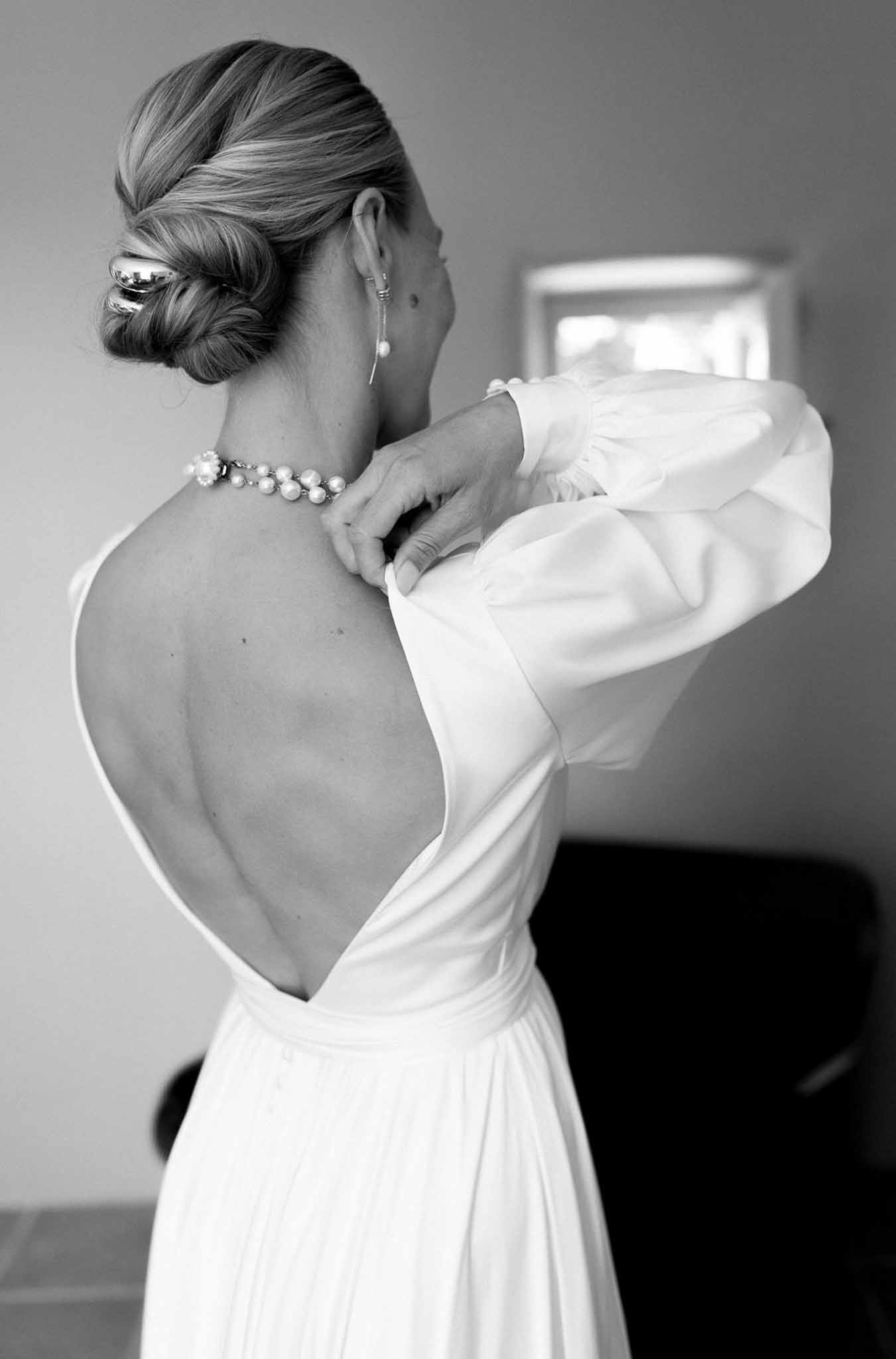 Bride adjusting dress during getting ready preparations in black and white portrait