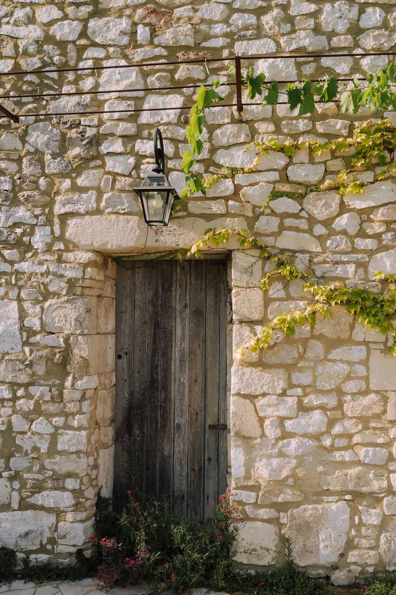 Stone building entrance with climbing vines and lantern at rustic countryside venue