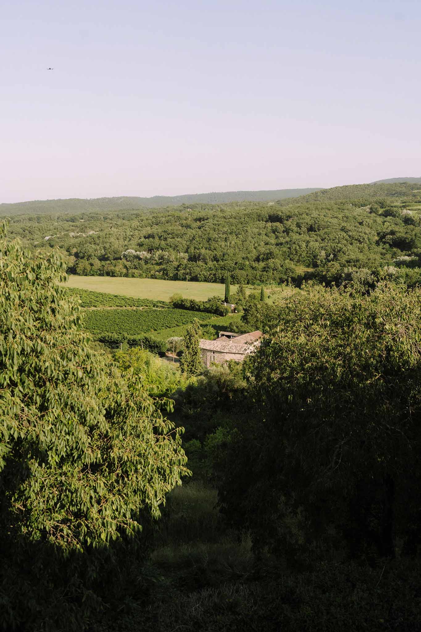 Aerial view of stone farmhouse wedding venue in Tuscan countryside with vineyards and rolling hills