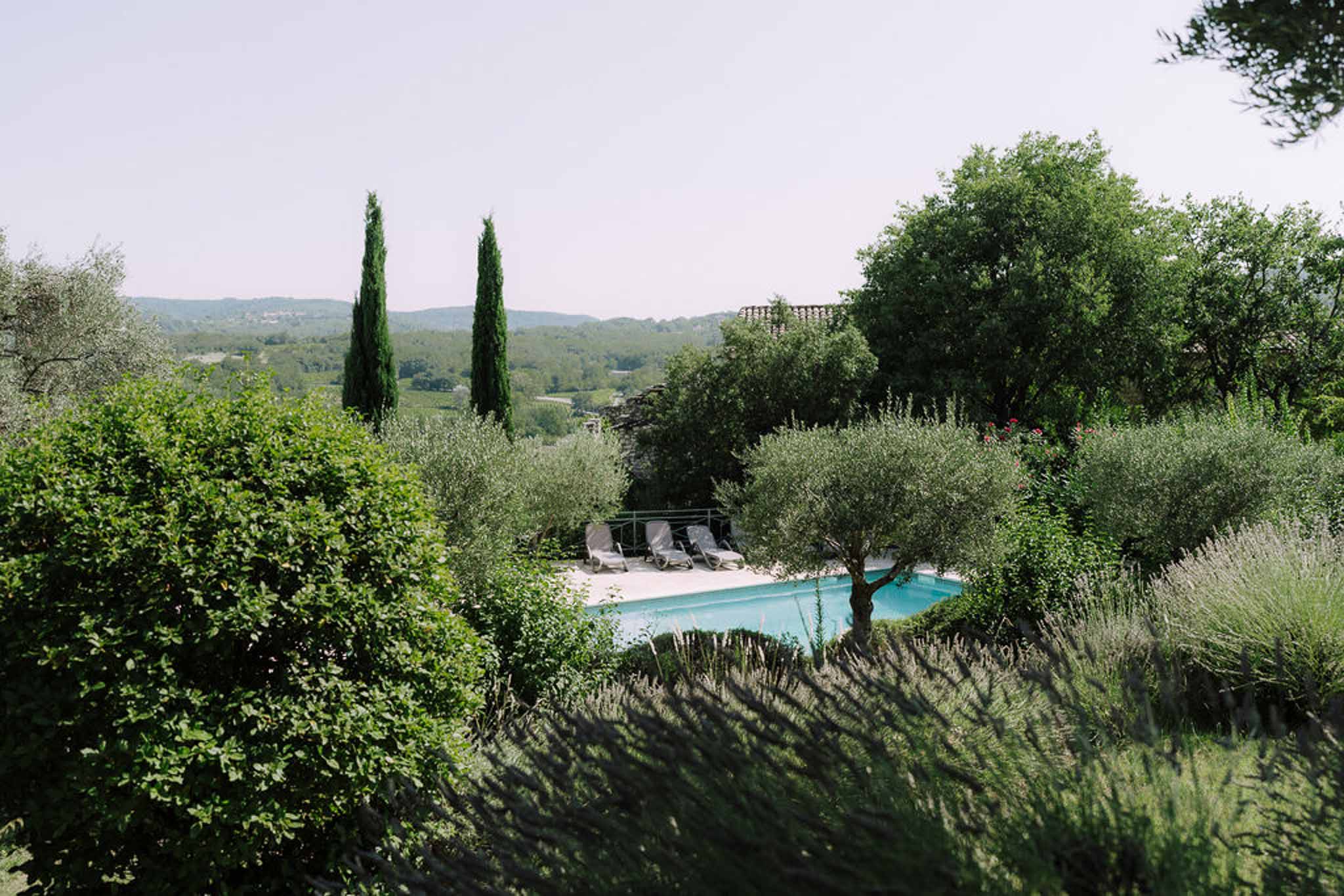 Wide-angle view of Mediterranean poolside wedding venue with olive trees and vineyard landscape
