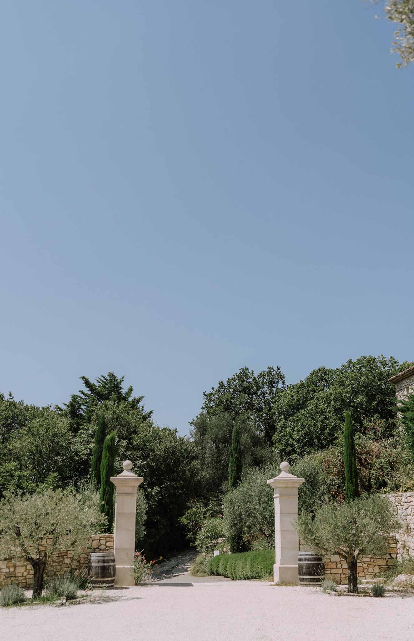 Stone gateway entrance with cypress trees at Mediterranean-style wedding venue