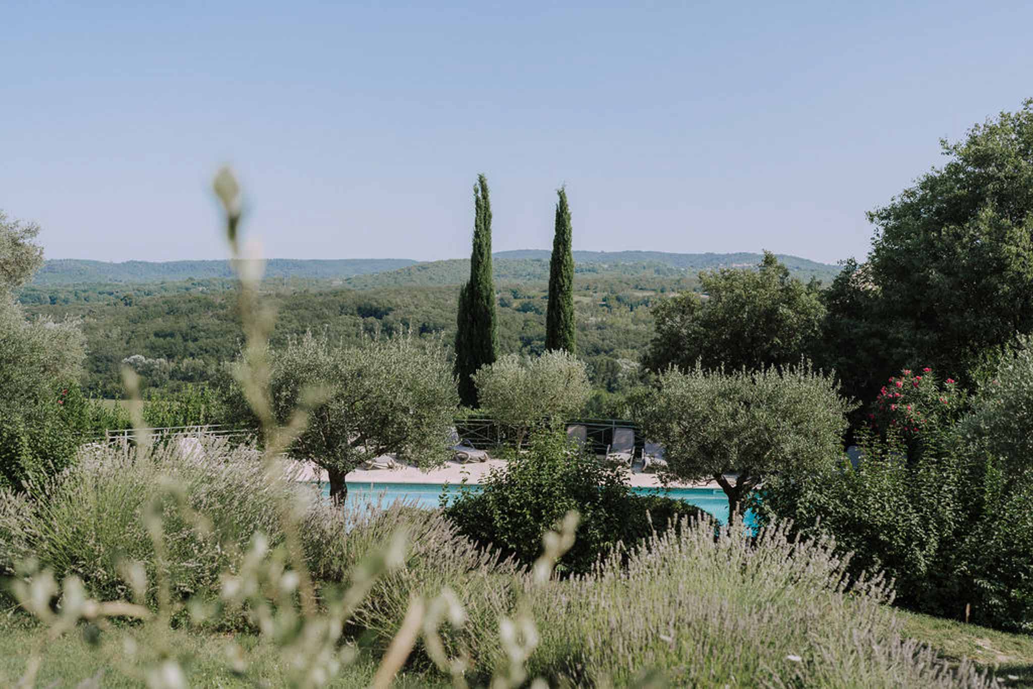 Tuscan wedding venue with swimming pool surrounded by cypress trees and lavender gardens in countryside setting