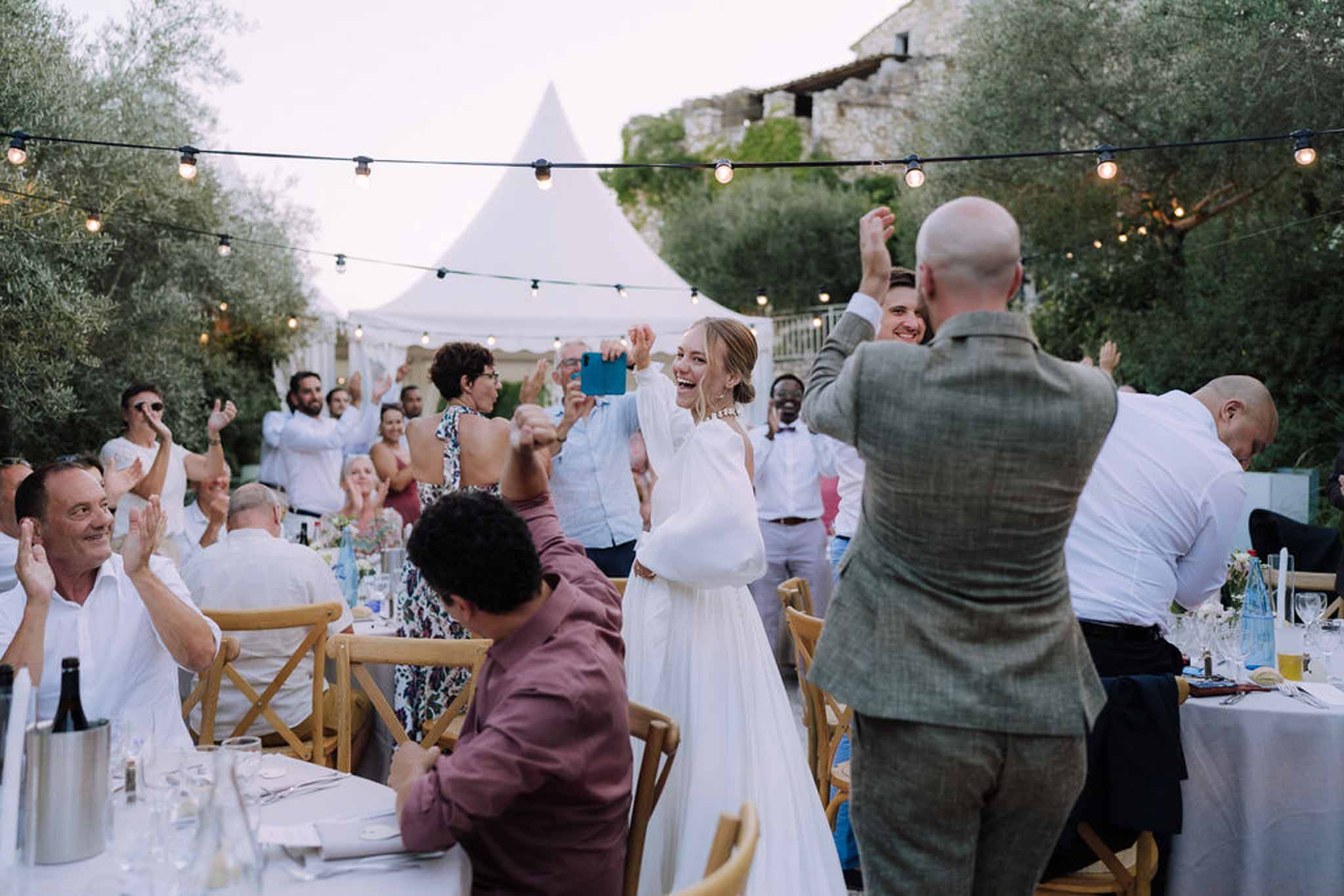 Bride and guests celebrating during outdoor reception dinner in garden courtyard with string lights