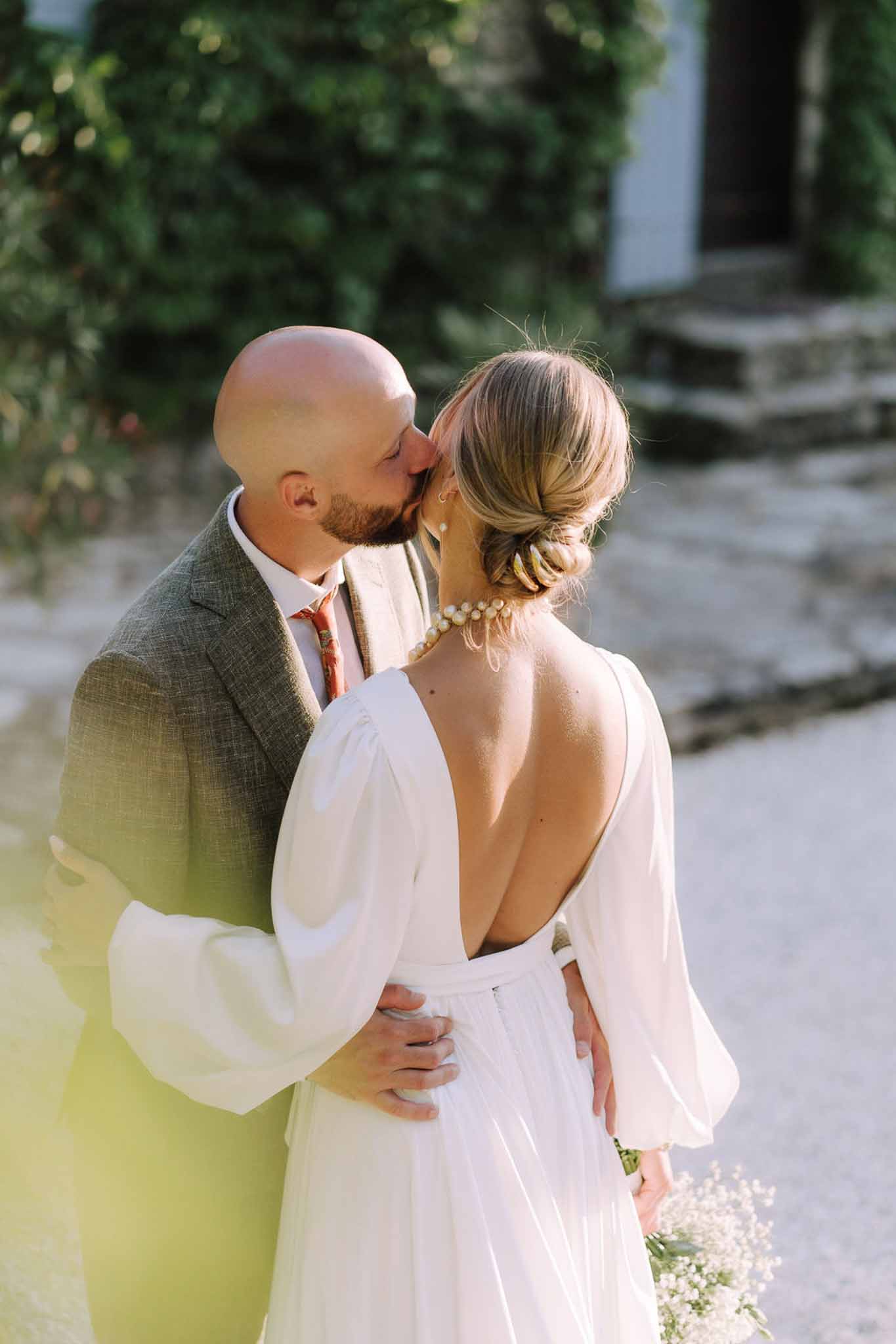 Bride and groom kissing in intimate portrait in ivy-covered courtyard