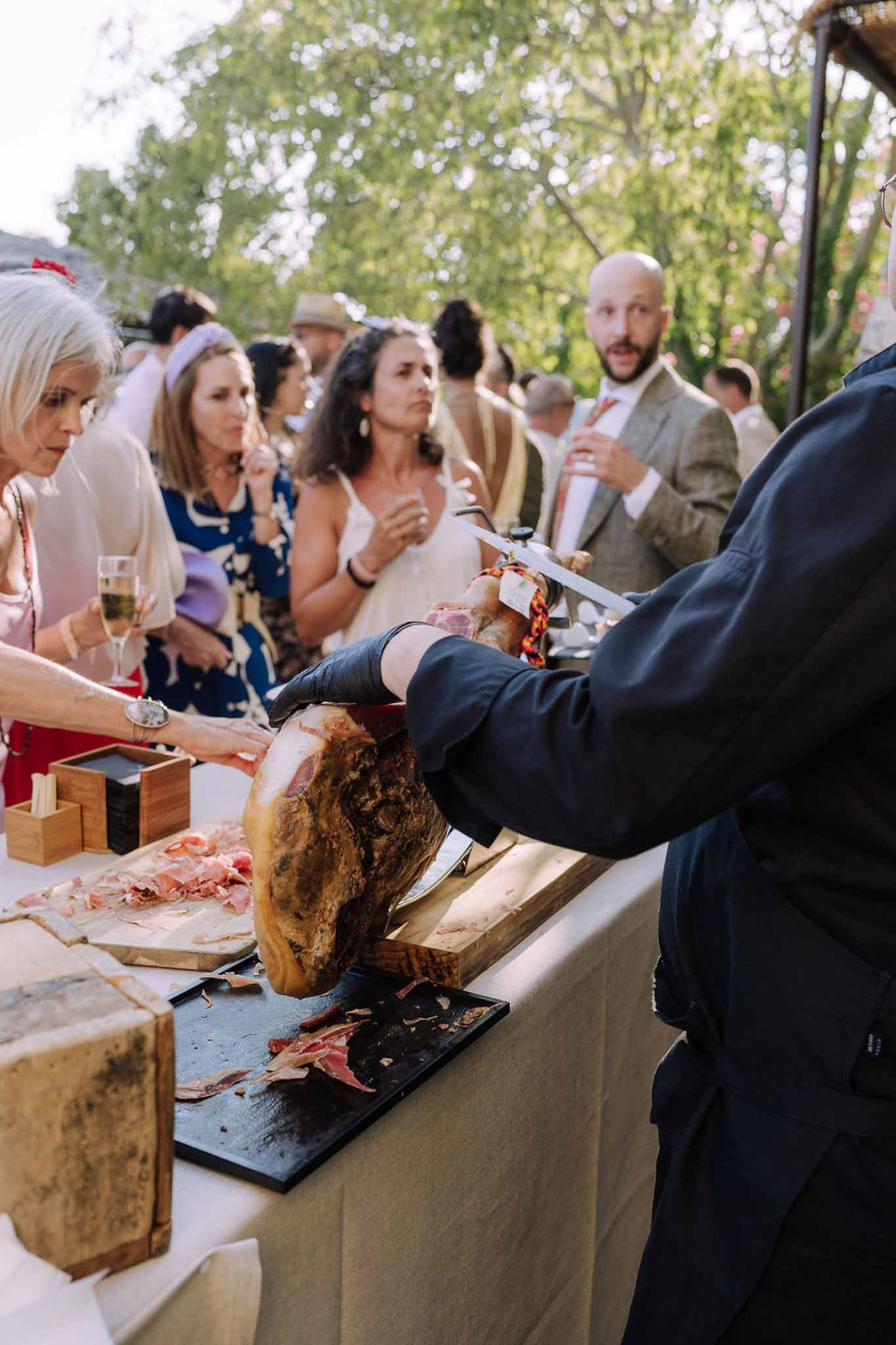 Jamón ibérico carving station during outdoor cocktail hour at garden wedding venue
