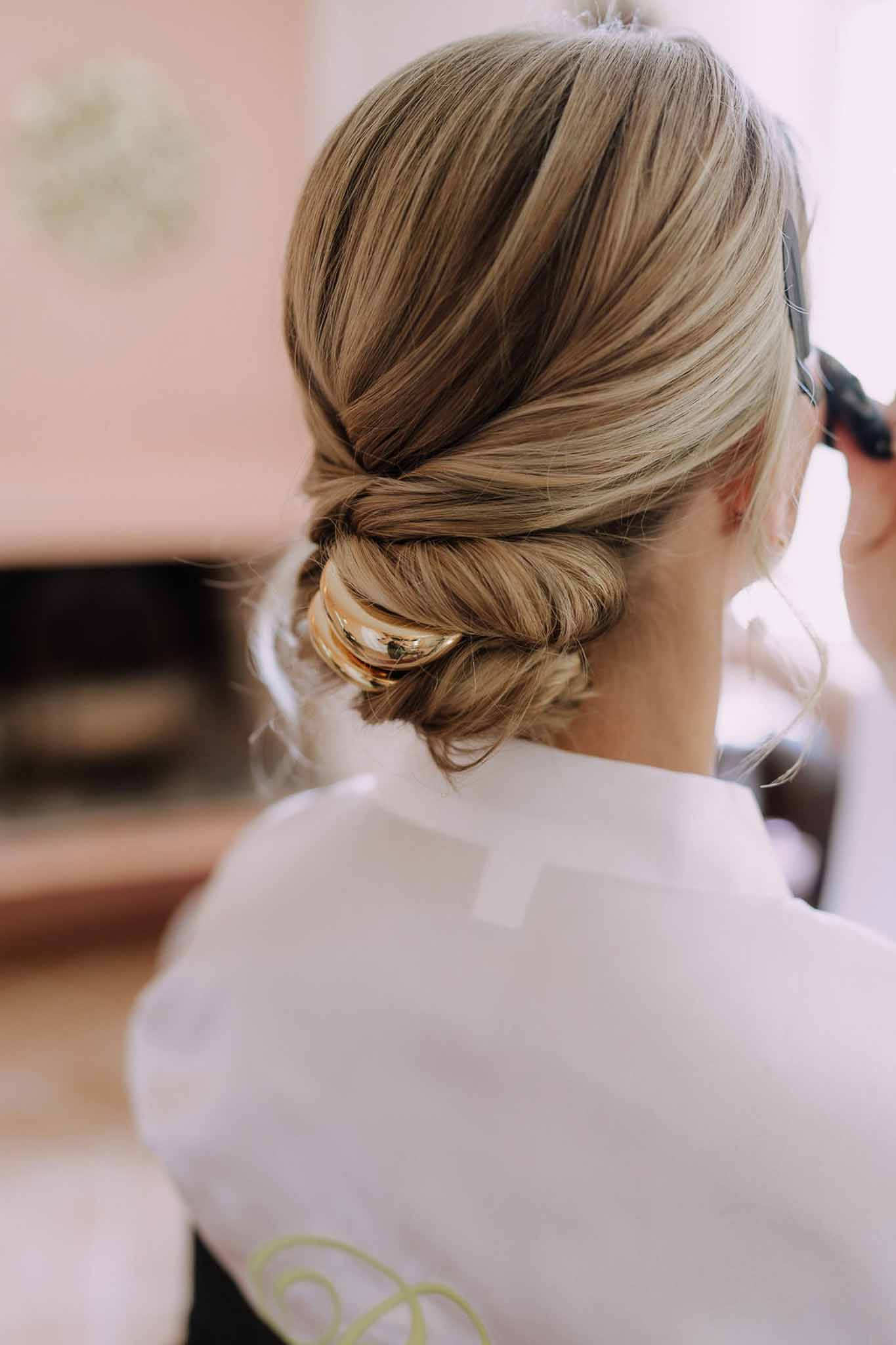 Close-up of bride's upswept hairstyle with gold hair accessory and white dress