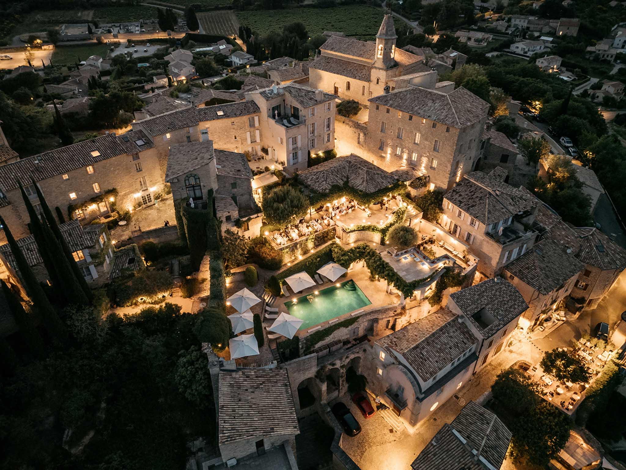 Aerial view of wedding reception at dusk in Tuscan villa courtyard with string lights and swimming pool