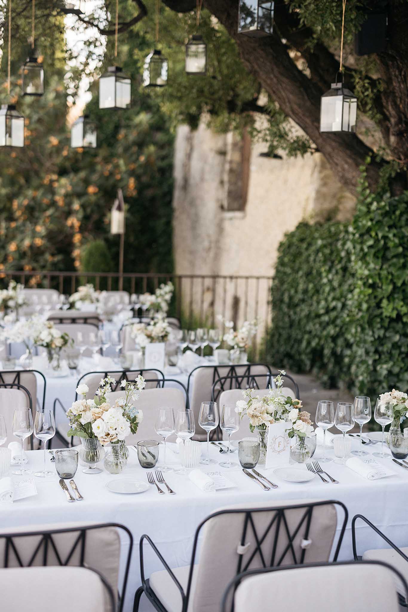 Elegant outdoor reception table setting with white linens and floral centerpieces in historic courtyard venue