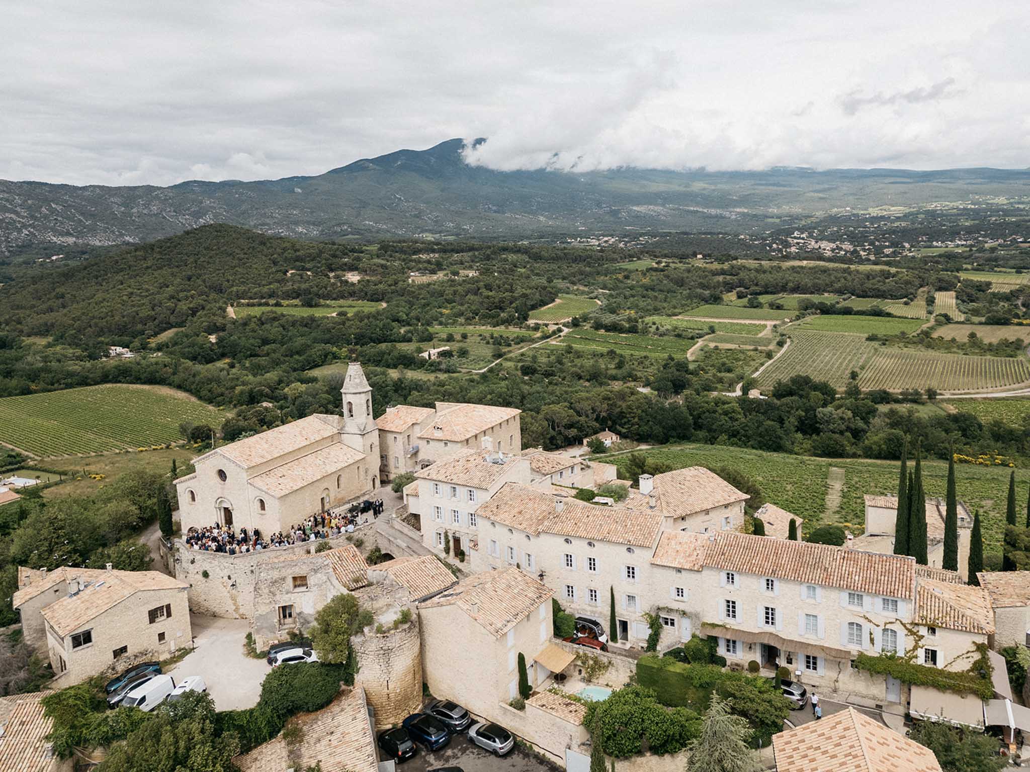 Aerial view of wedding ceremony at Provençal stone chapel surrounded by vineyard landscape