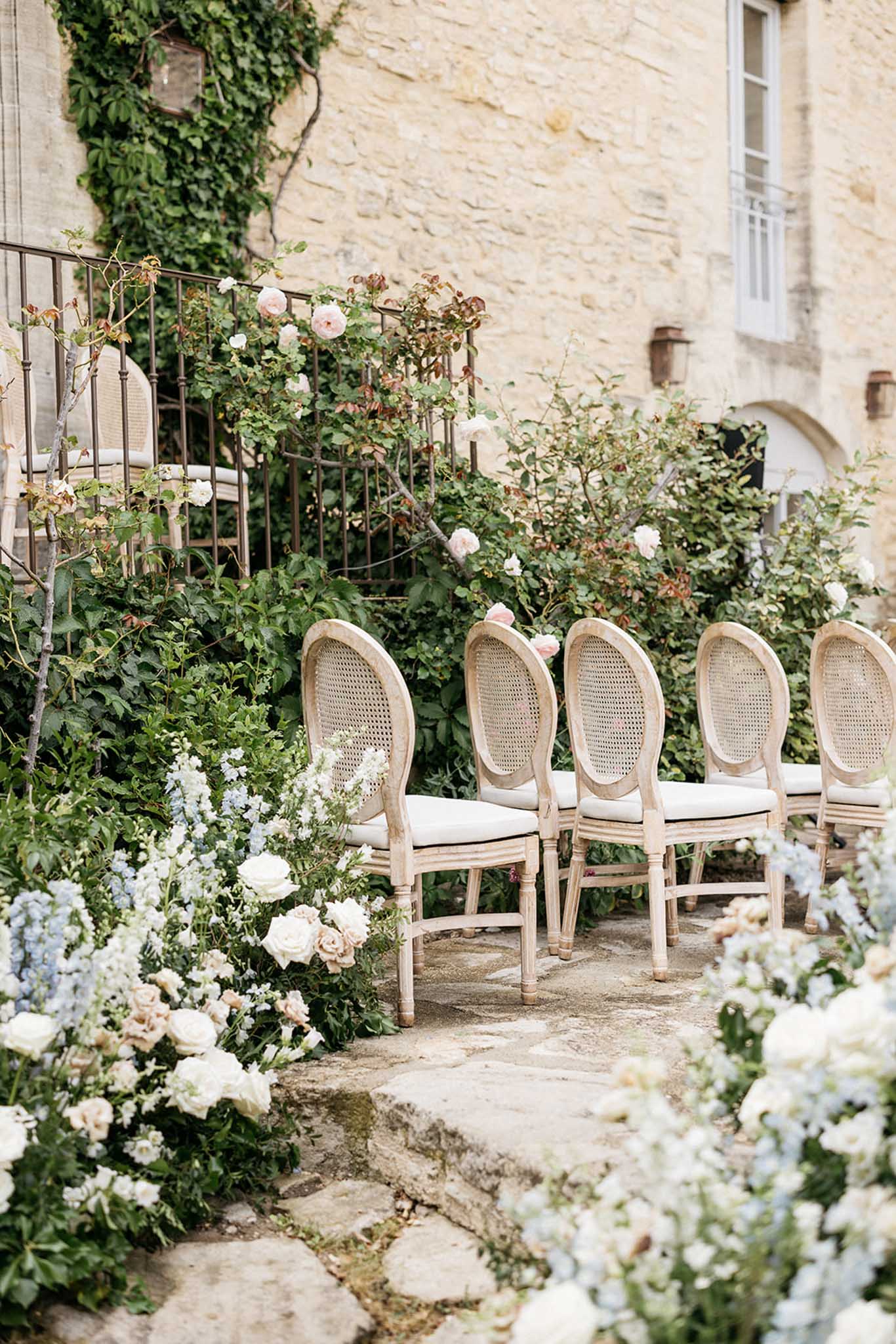 Ceremony setup with wooden chairs and floral arrangements in European courtyard venue