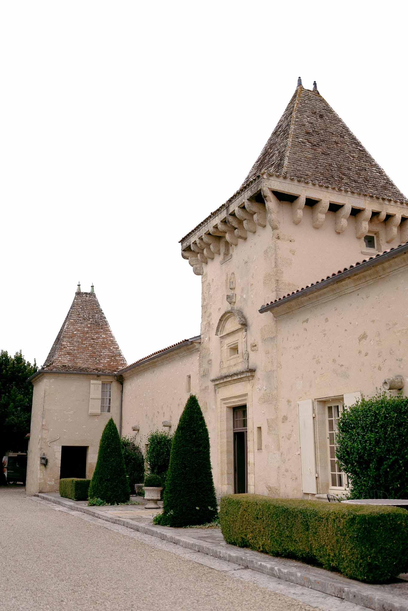 French chateau with twin conical-roofed towers gravel drive conical topiary and carved stone doorway